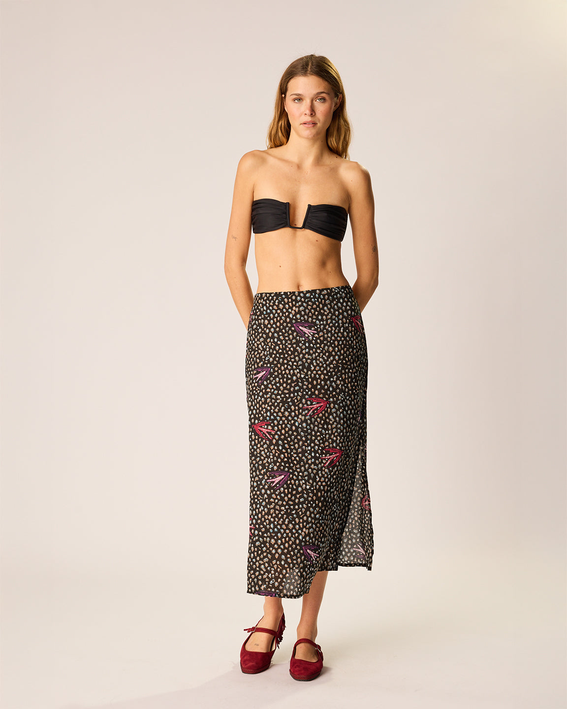 Woman wearing a black strapless top and patterned skirt on a plain background
