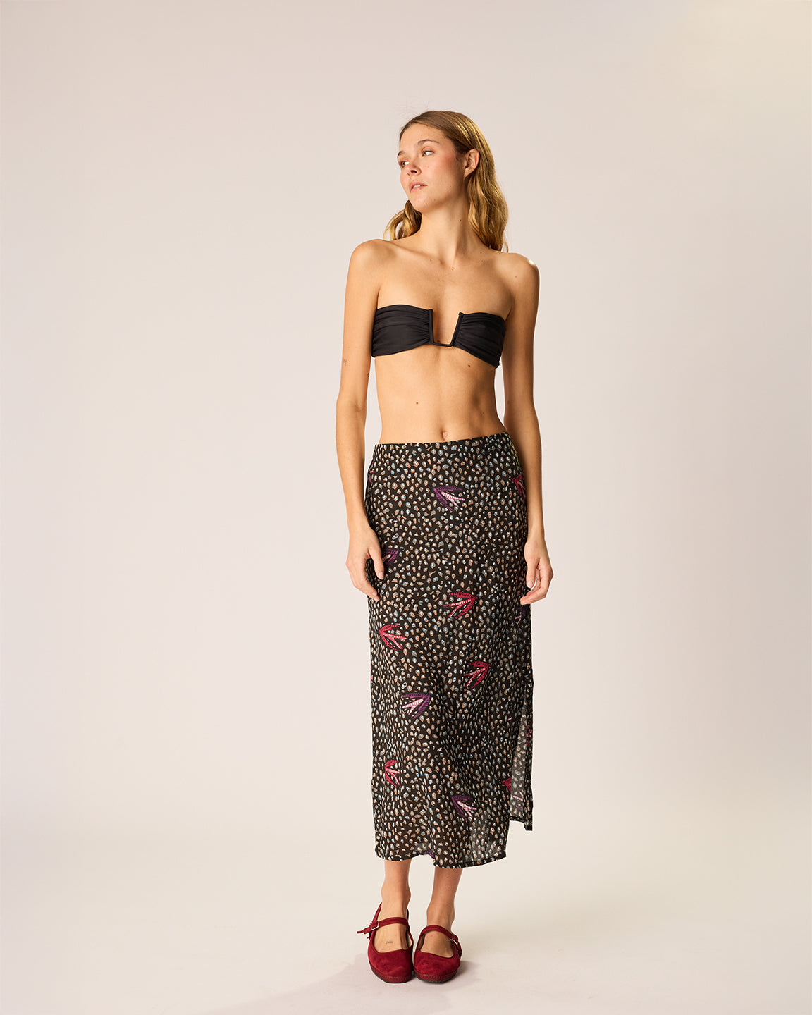 Woman wearing a black strapless top and patterned skirt on a plain background