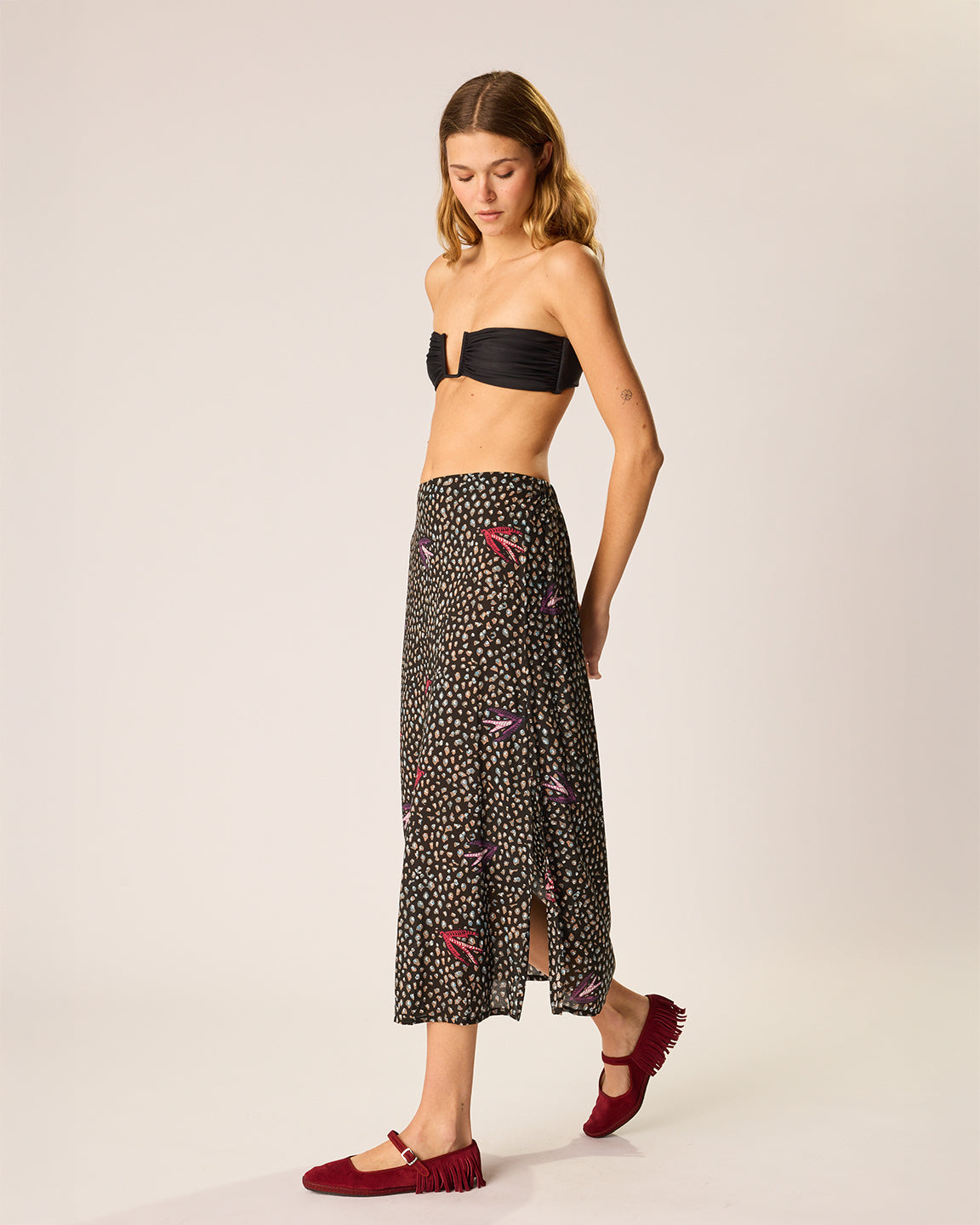 Woman wearing a black strapless top and patterned skirt on a white background