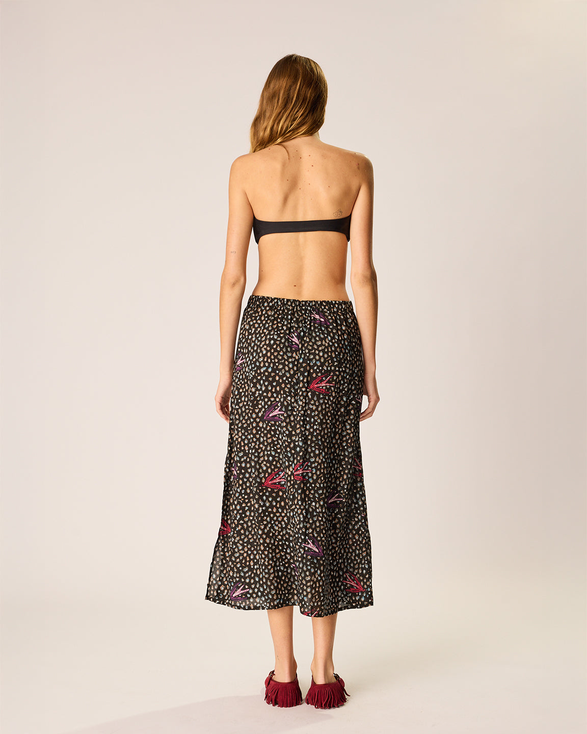 Woman wearing a black floral patterned skirt on a plain background