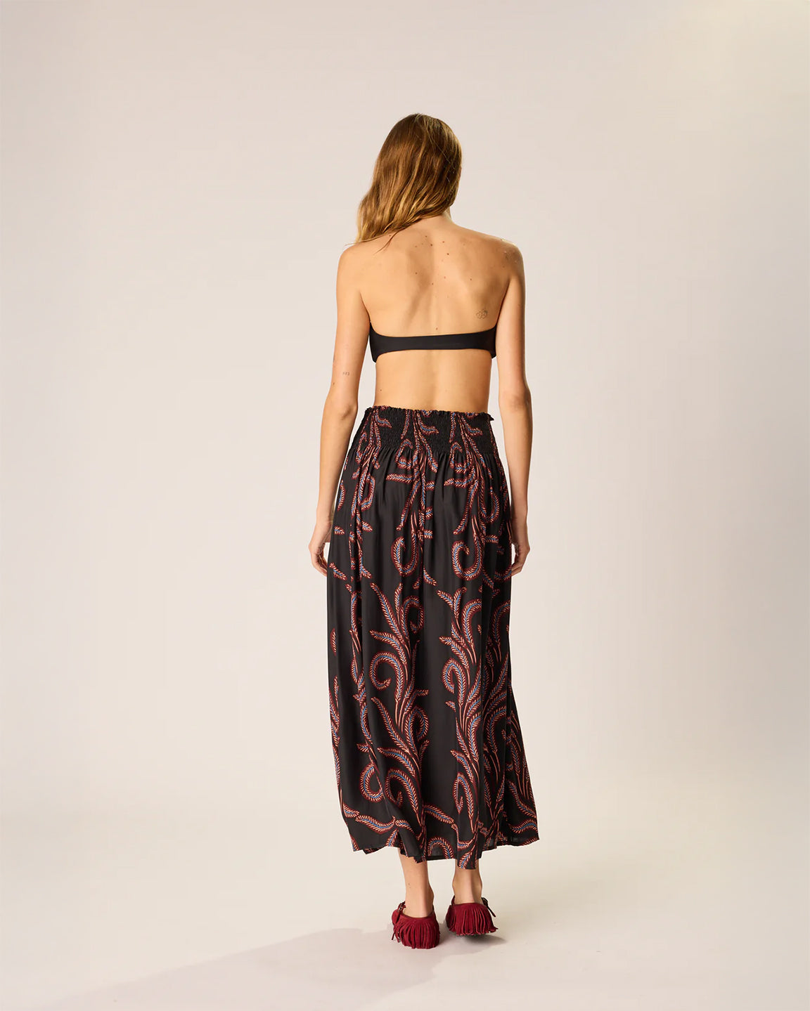 Woman wearing a black and red patterned outfit on a plain background