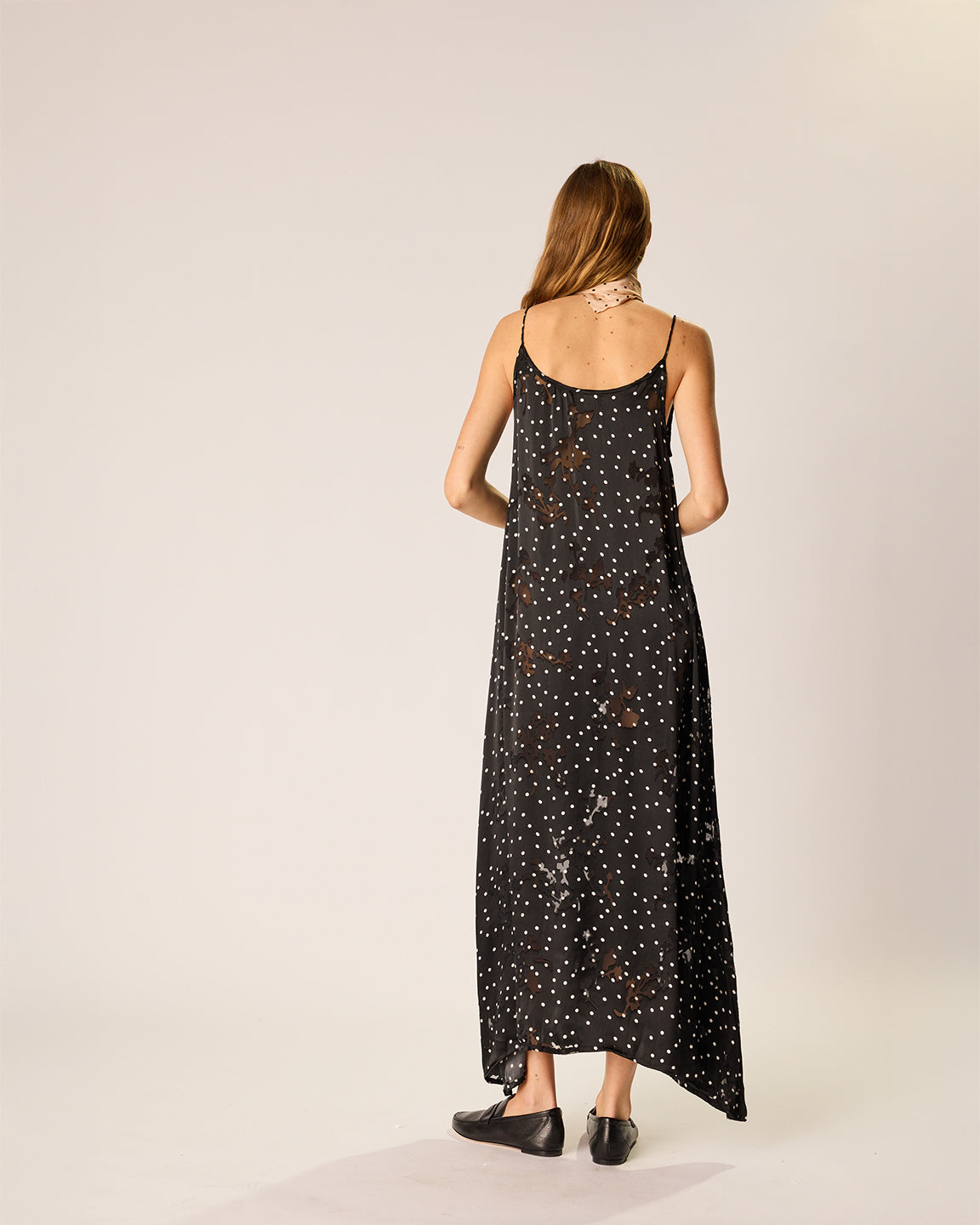 Woman wearing a black dress with white polka dots on a beige background