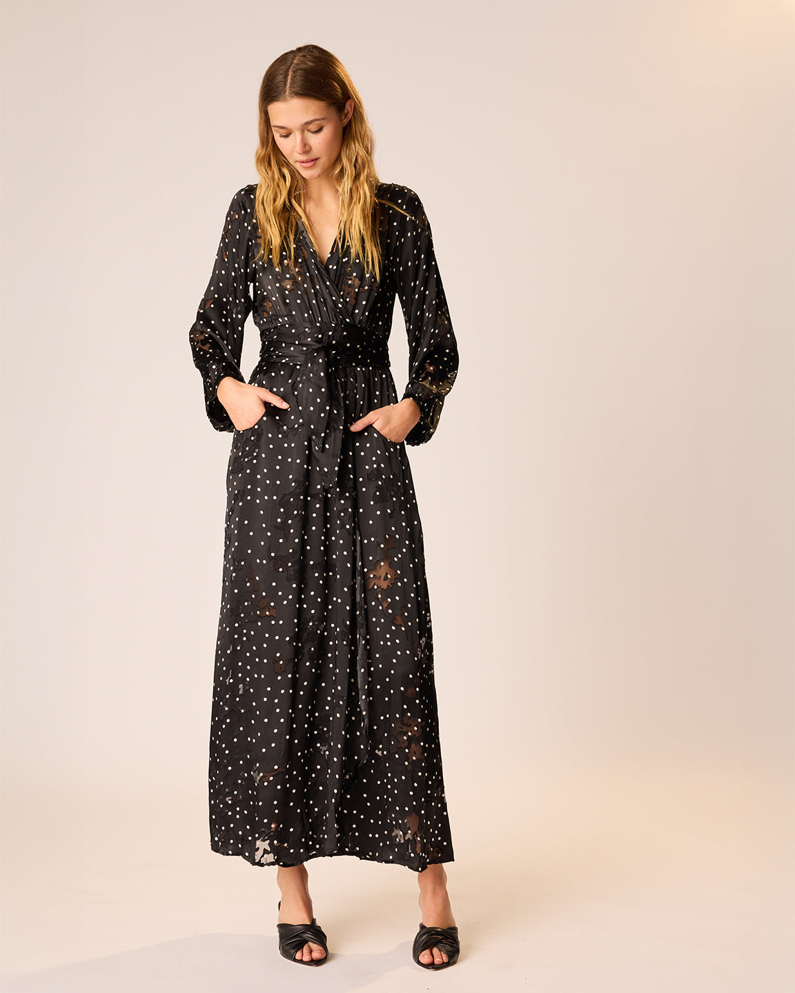 Woman wearing a black polka dot dress on a beige background