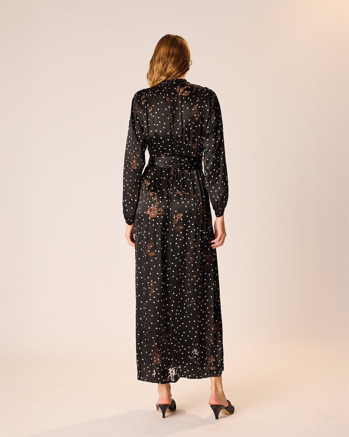 Woman wearing a black dress with floral patterns on a beige background