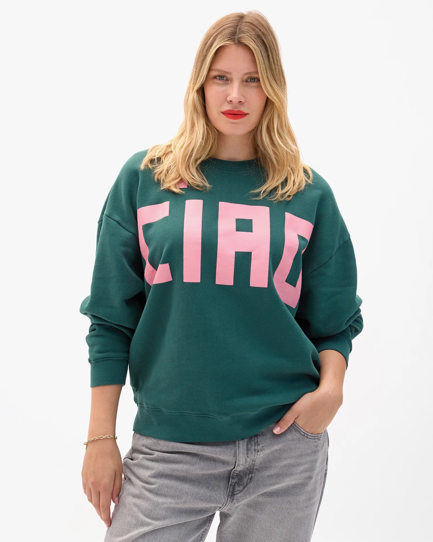 Woman wearing a green sweatshirt with pink letters on a white background