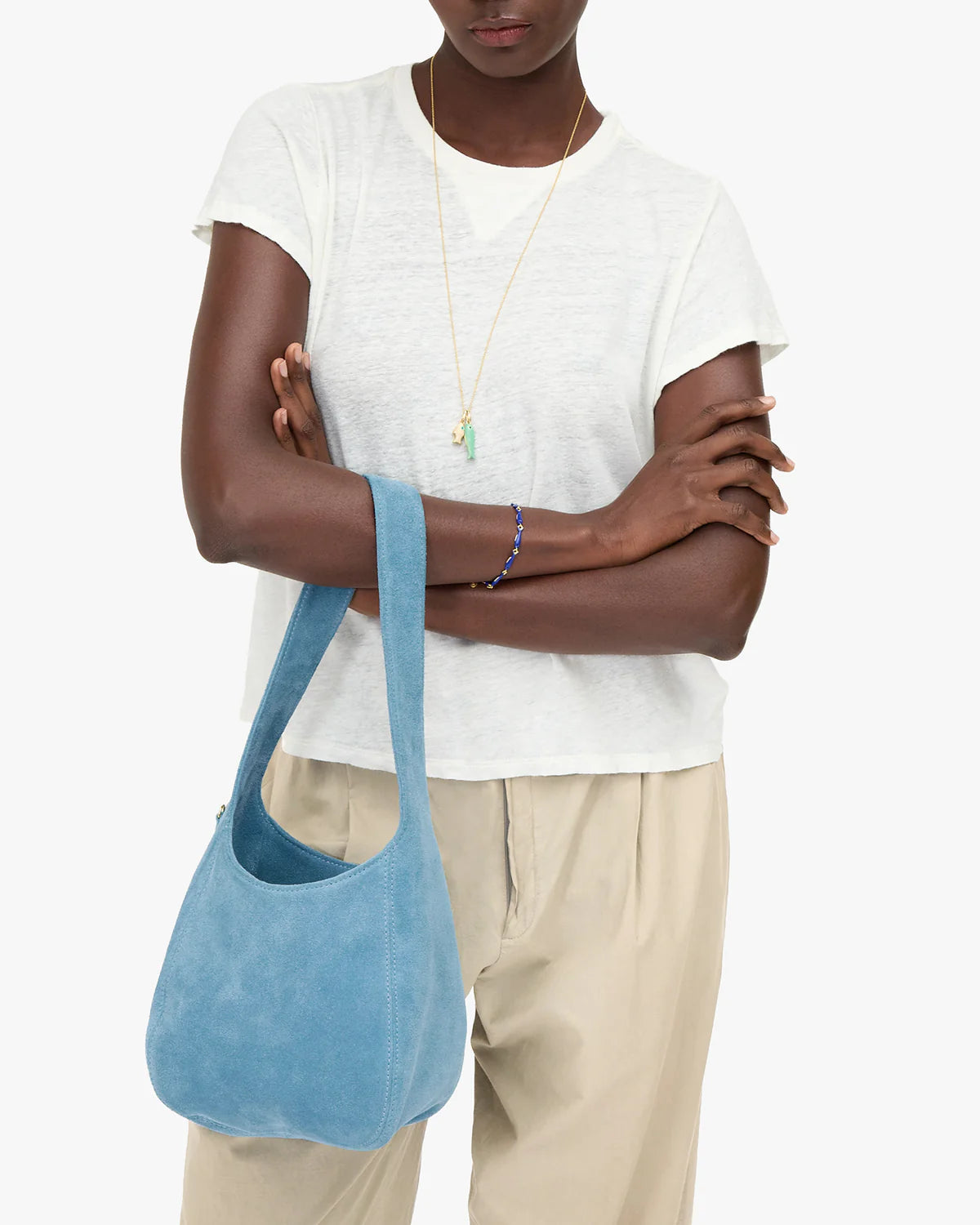Person wearing a white top and beige pants with a blue handbag on a white background