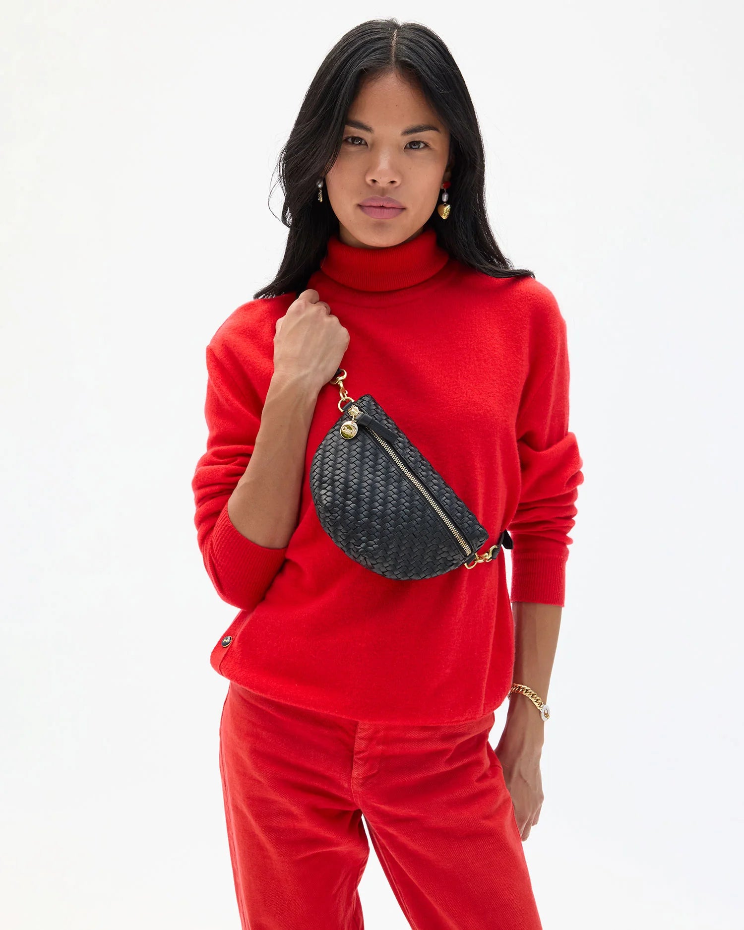 Woman wearing a red outfit with a black woven bag on a white background