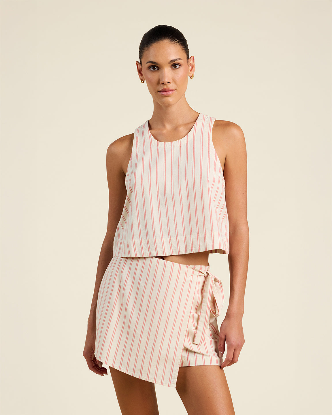 Woman wearing a pink and white striped outfit on a beige background
