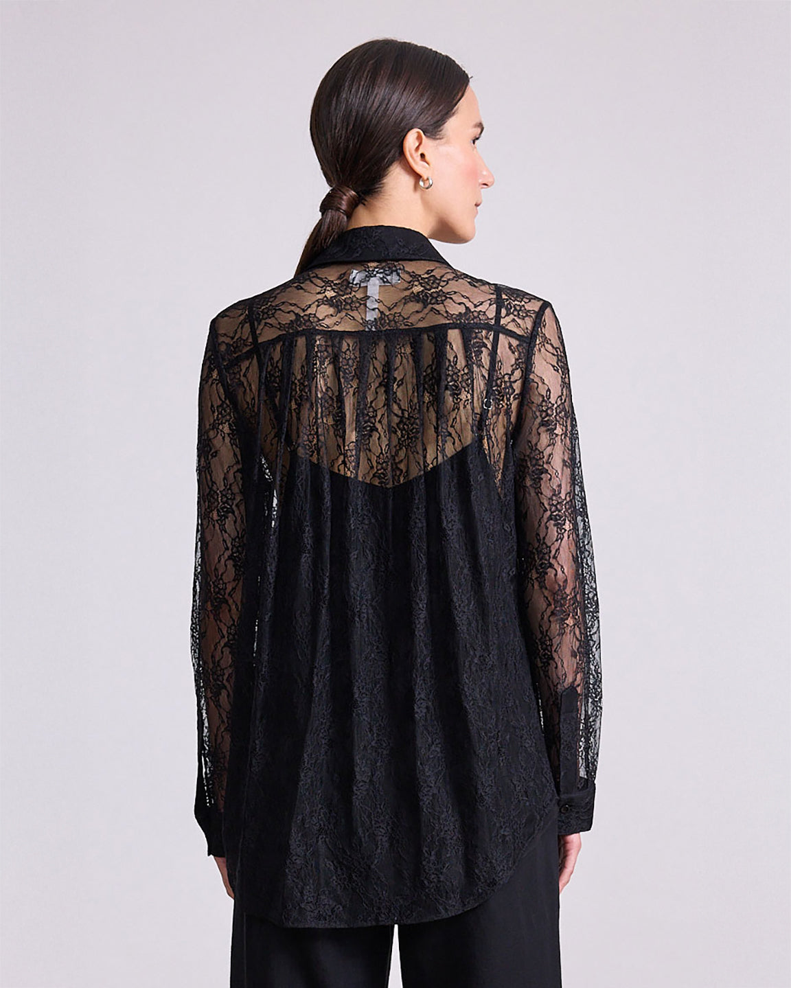 Black lace shirt worn by a person on a light gray background
