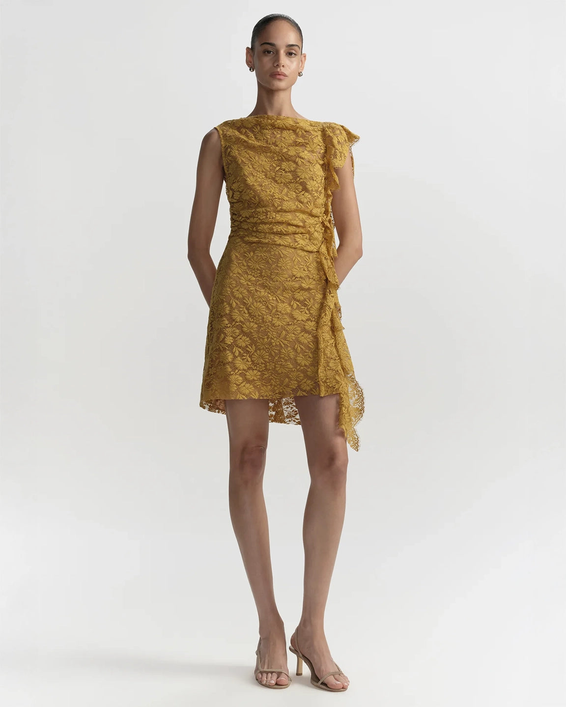Woman wearing a mustard yellow lace dress on a white background