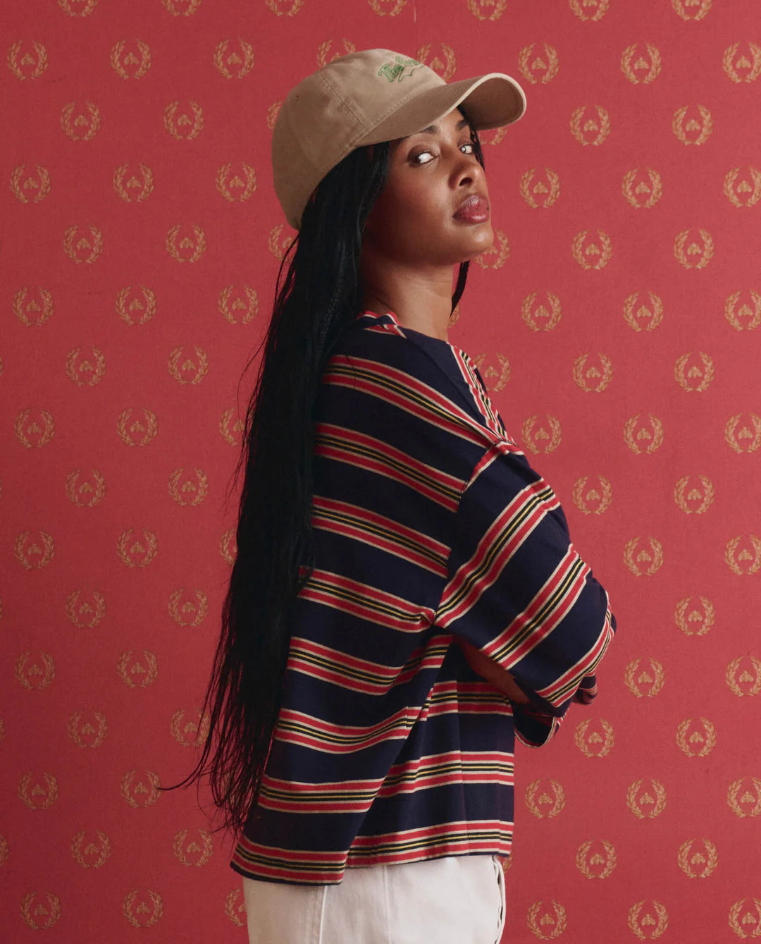 Woman wearing a striped shirt and cap against a red patterned background
