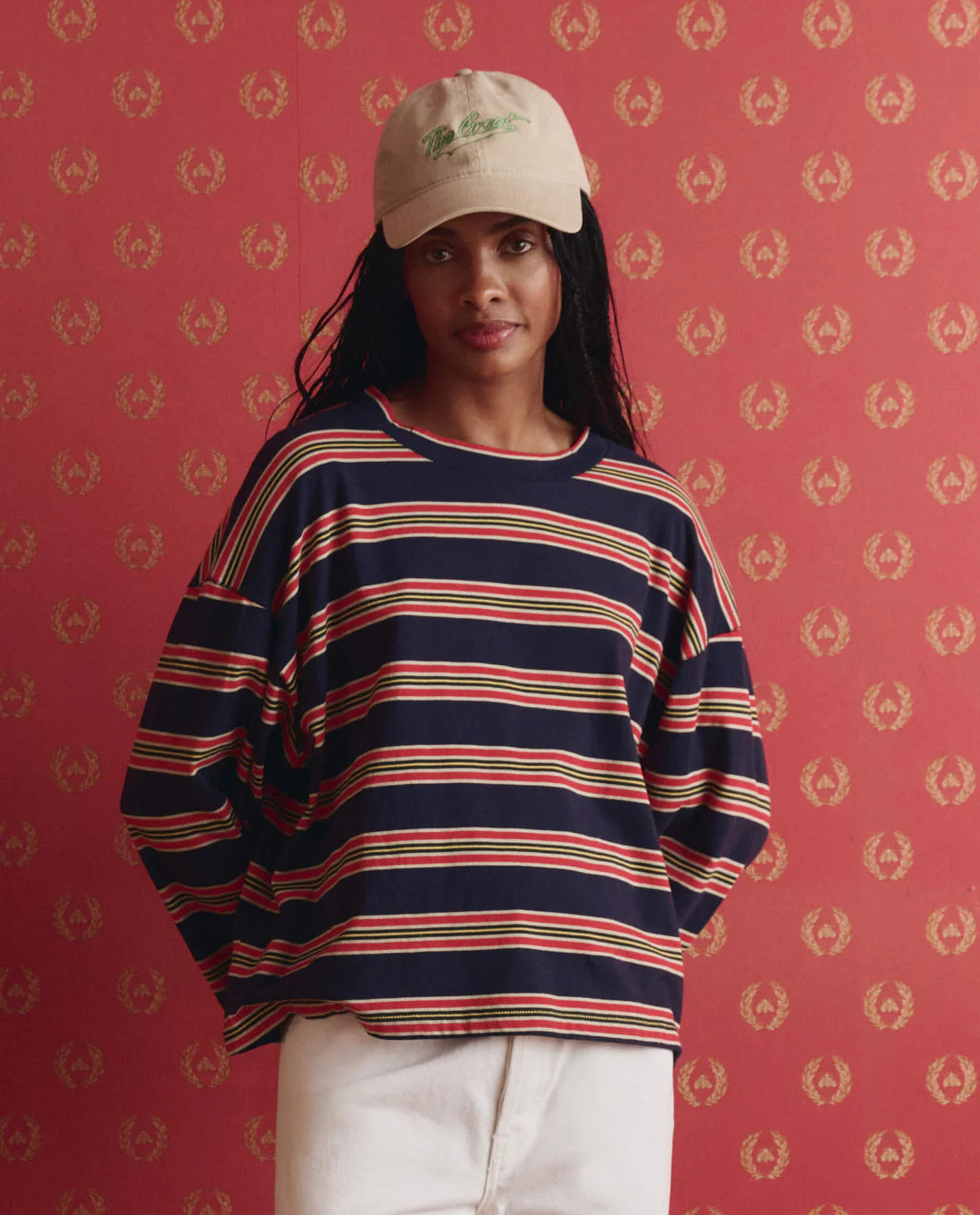 Person wearing a striped sweater and cap against a patterned red background