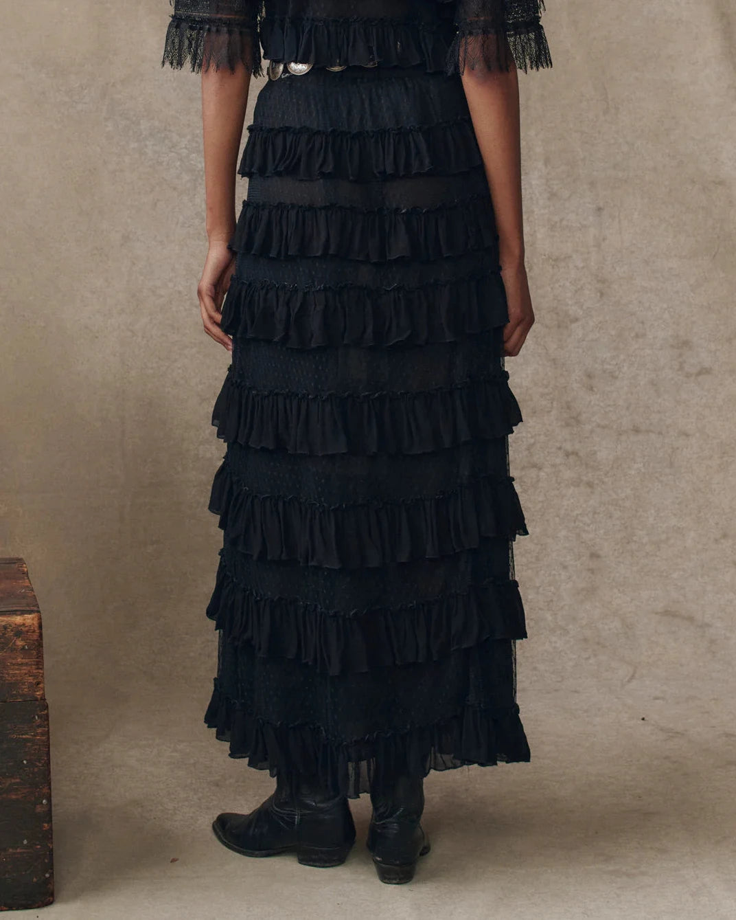 Black ruffled dress worn by a person on a beige background