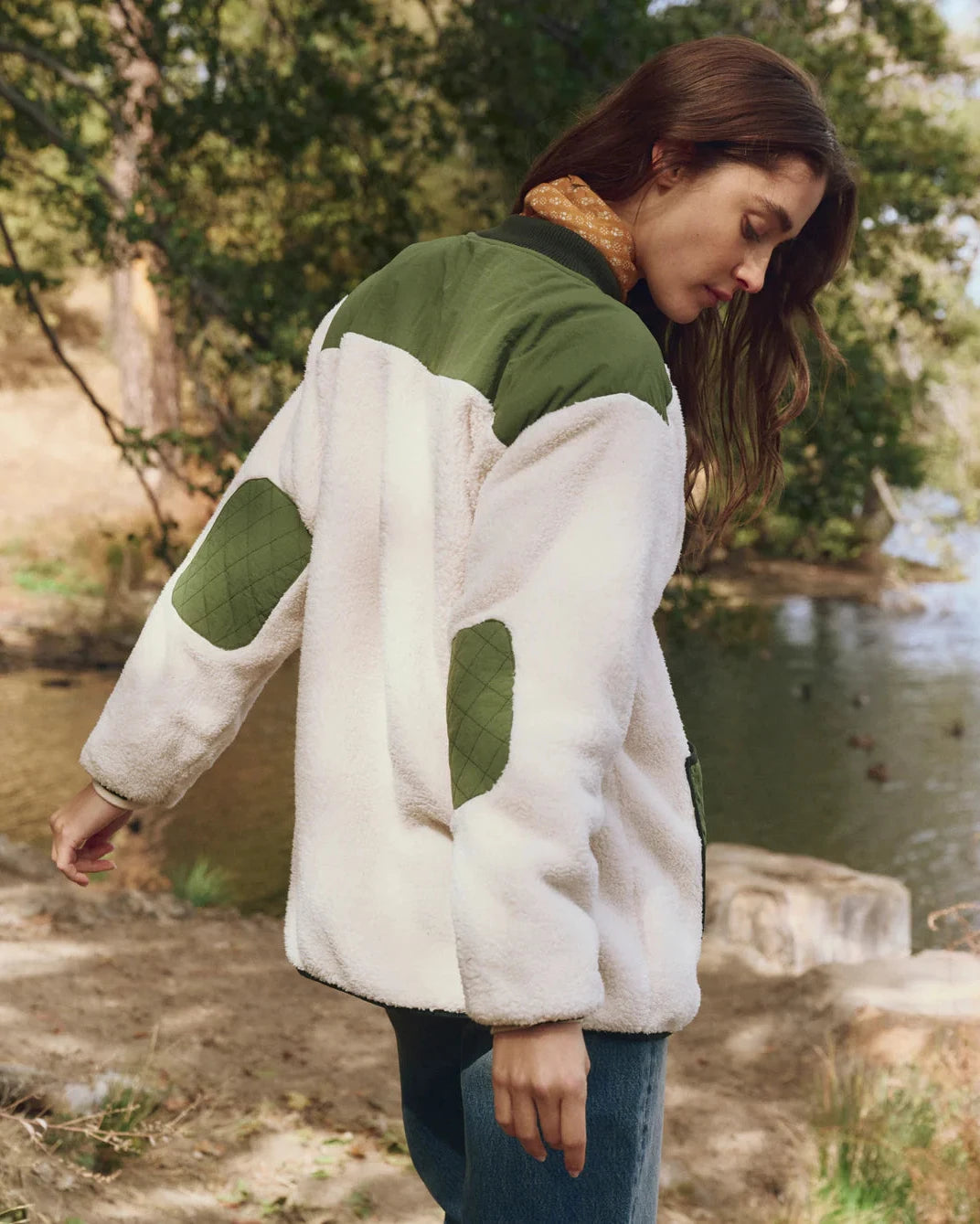 Woman wearing a white and green jacket by a lake