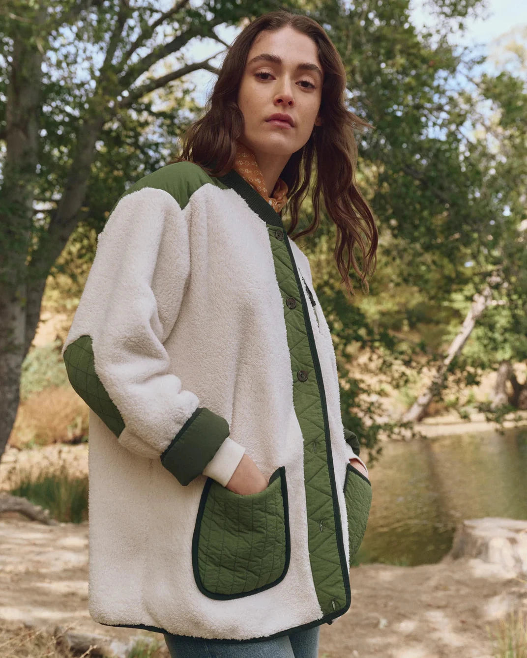 Woman wearing a green and white jacket outdoors by a lake
