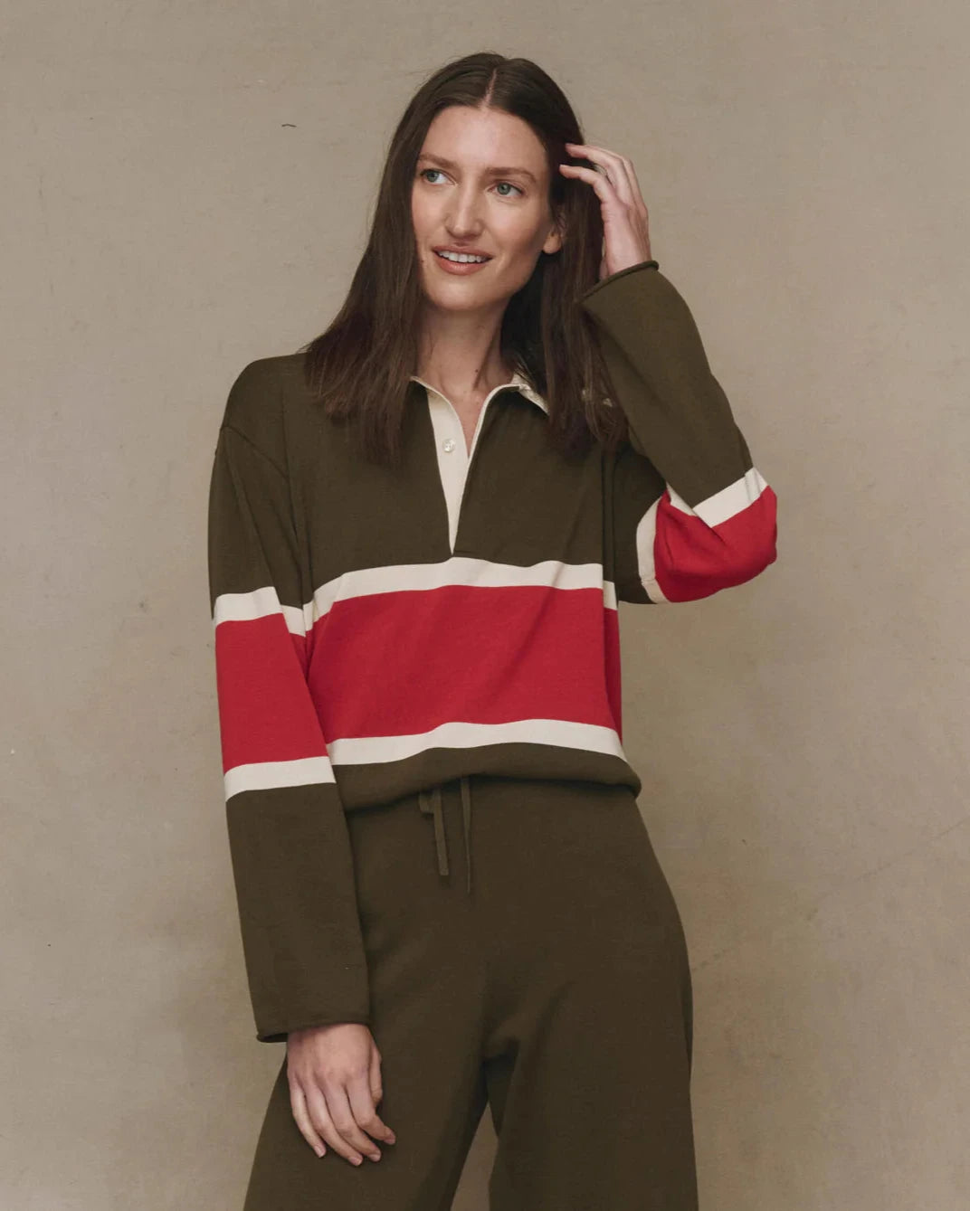 Woman wearing a green and red striped sweater against a beige background
