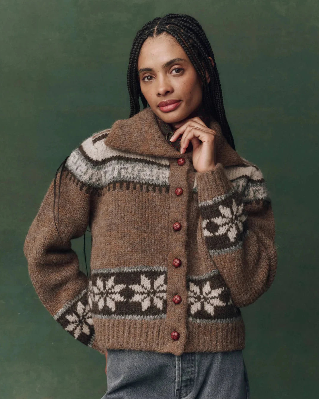 Woman wearing a brown knitted cardigan with patterned design against a green background