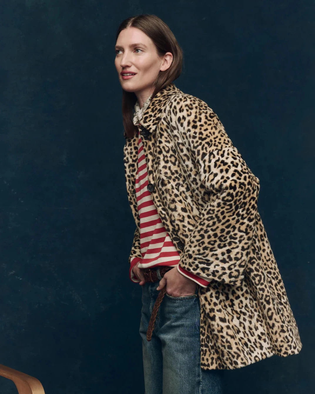 Woman wearing a leopard print coat over a striped shirt against a dark blue background