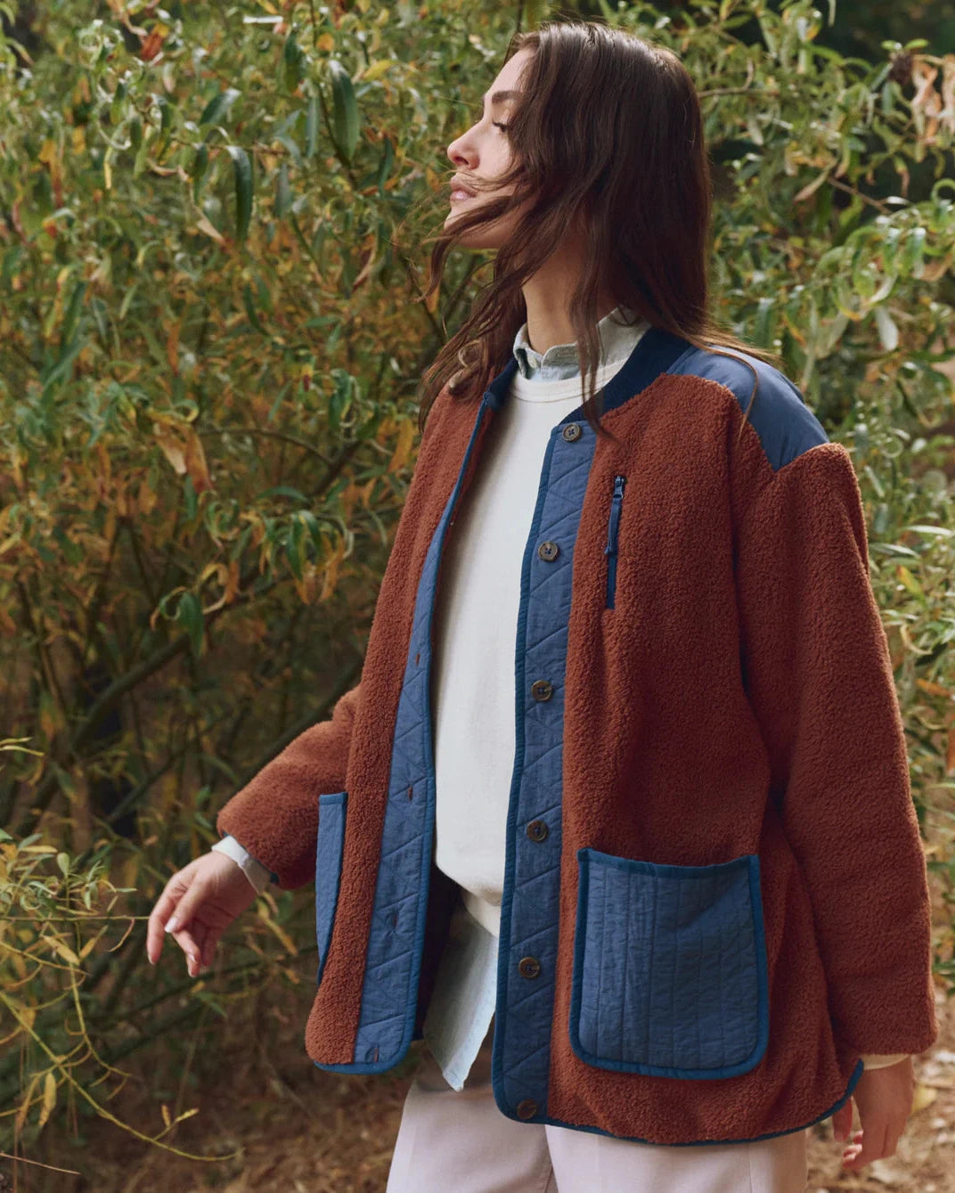 Person wearing a brown and blue jacket in a natural setting