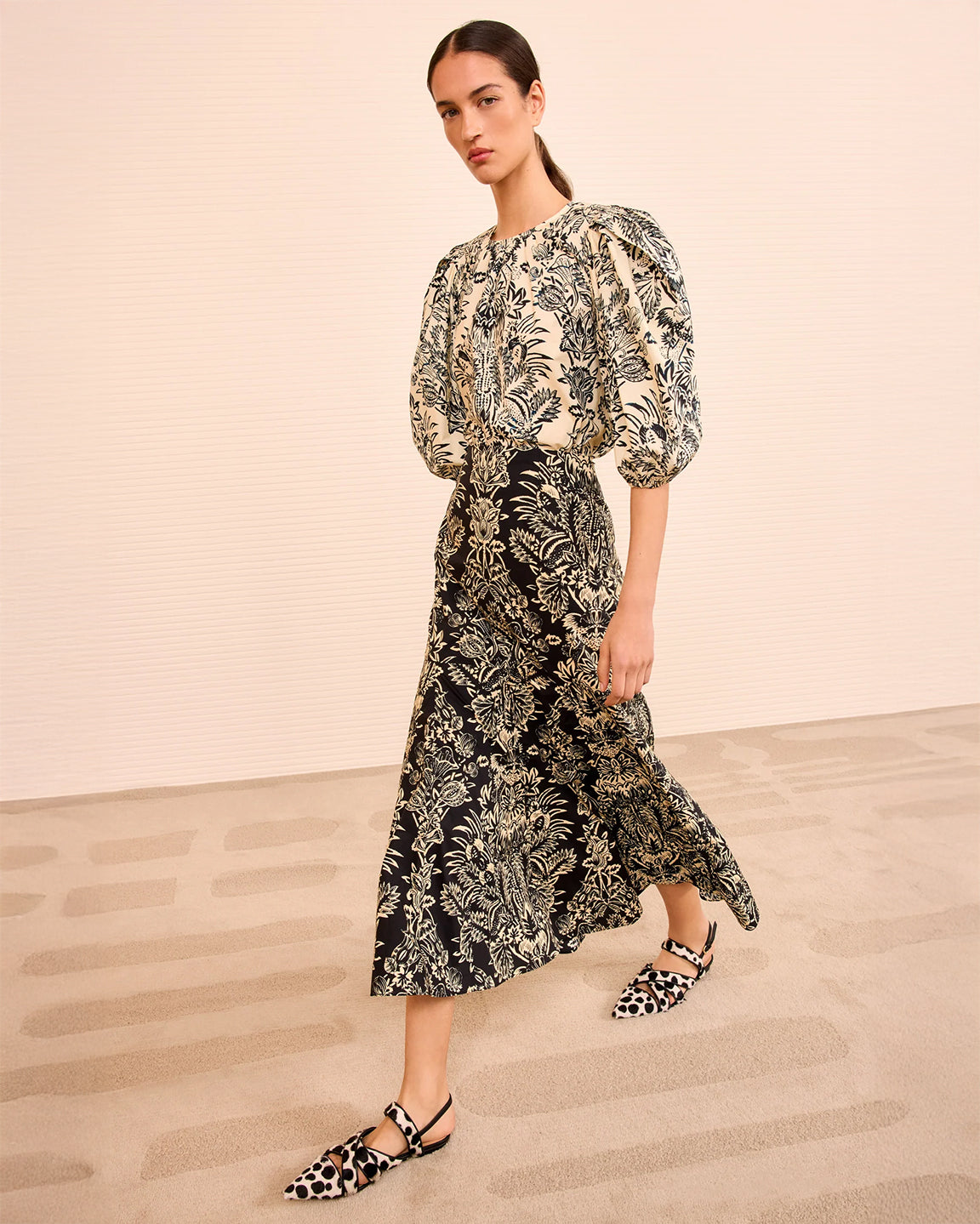 Woman wearing a floral dress with puff sleeves on a beige background