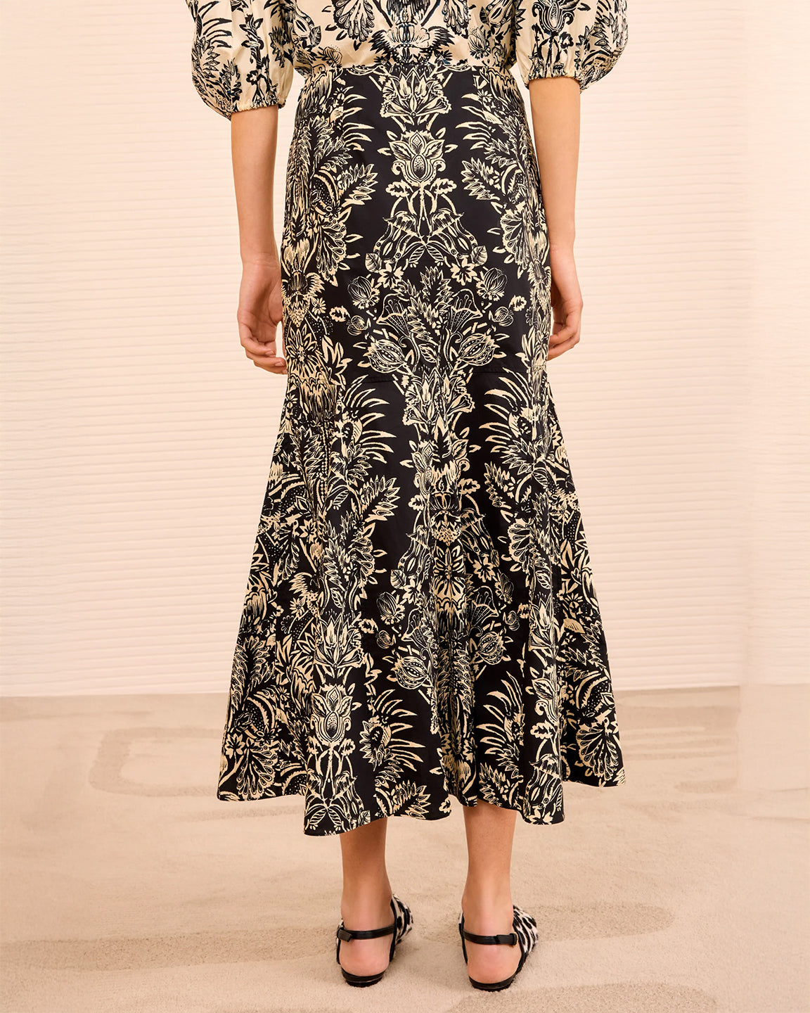 Person wearing a black floral dress on a beige background