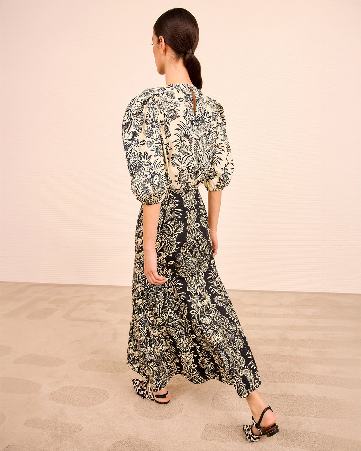 Woman wearing a floral dress with puff sleeves in a minimalistic setting