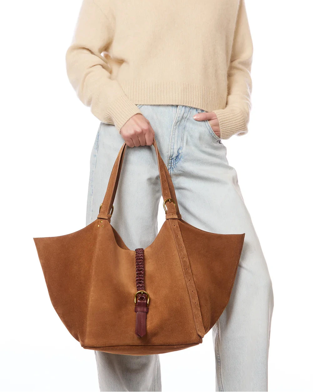Person holding a brown leather handbag against a plain background