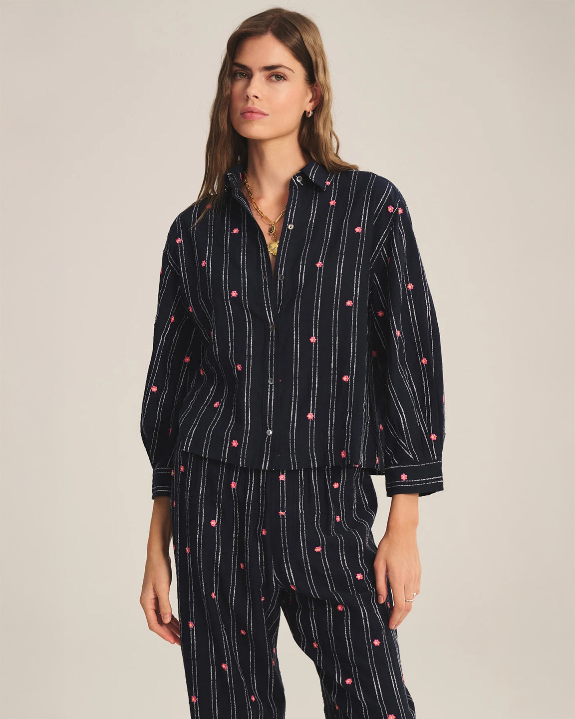 Woman wearing a black pajama set with white and red polka dots on a beige background