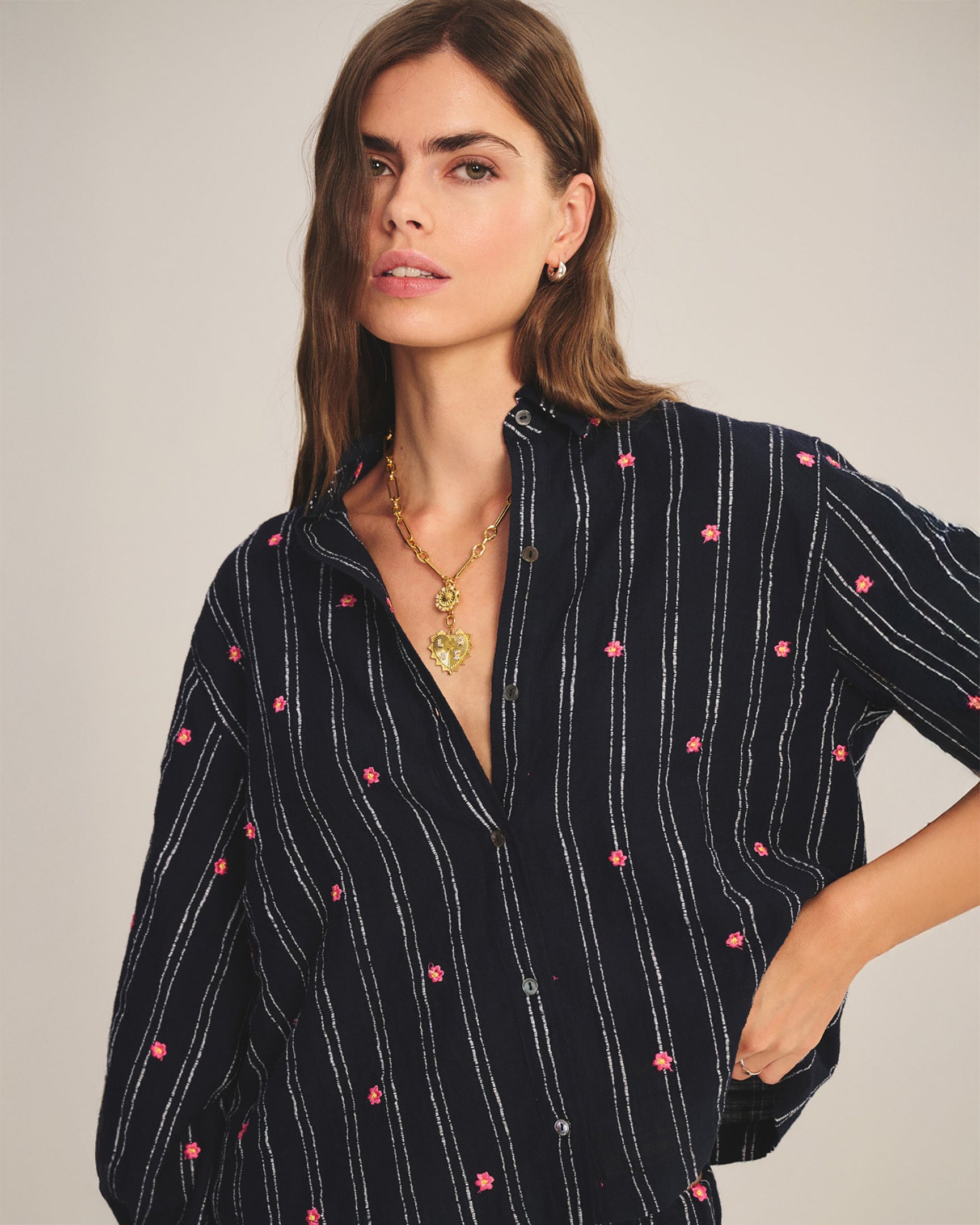 Woman wearing a black shirt with pink polka dots against a plain background