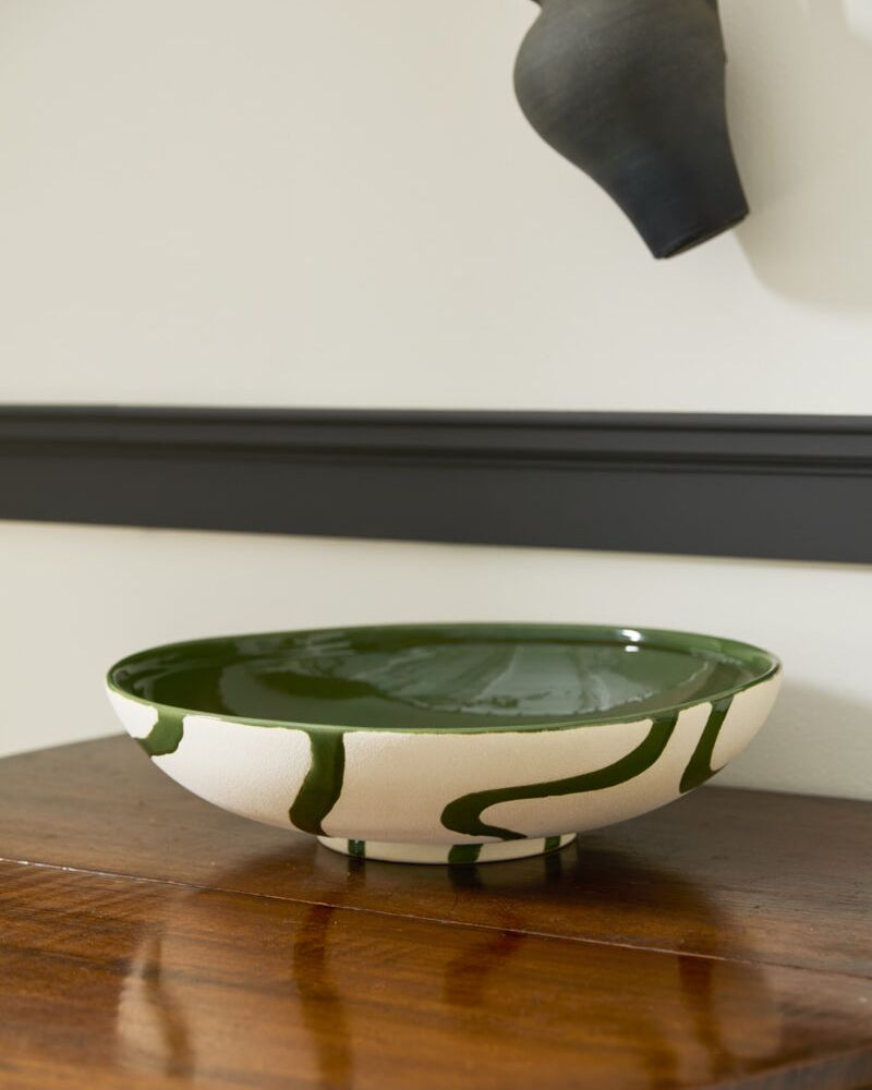 Ceramic bowl with green design on a wooden surface