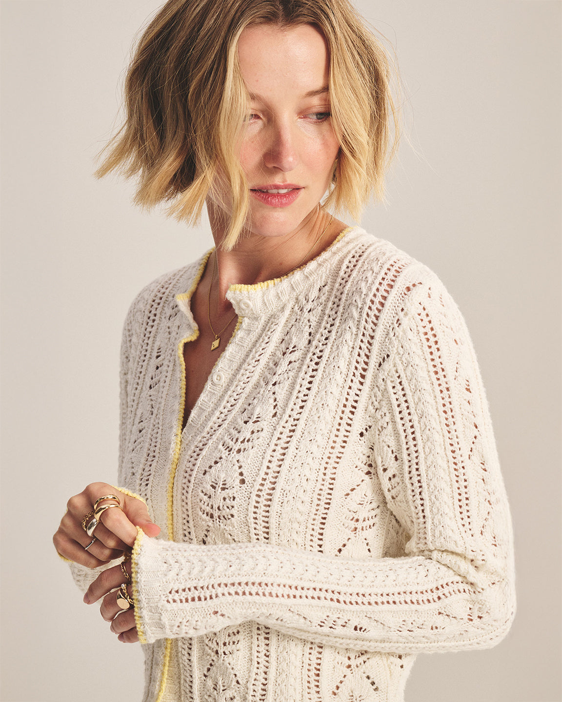 Woman wearing a white lace cardigan against a plain background