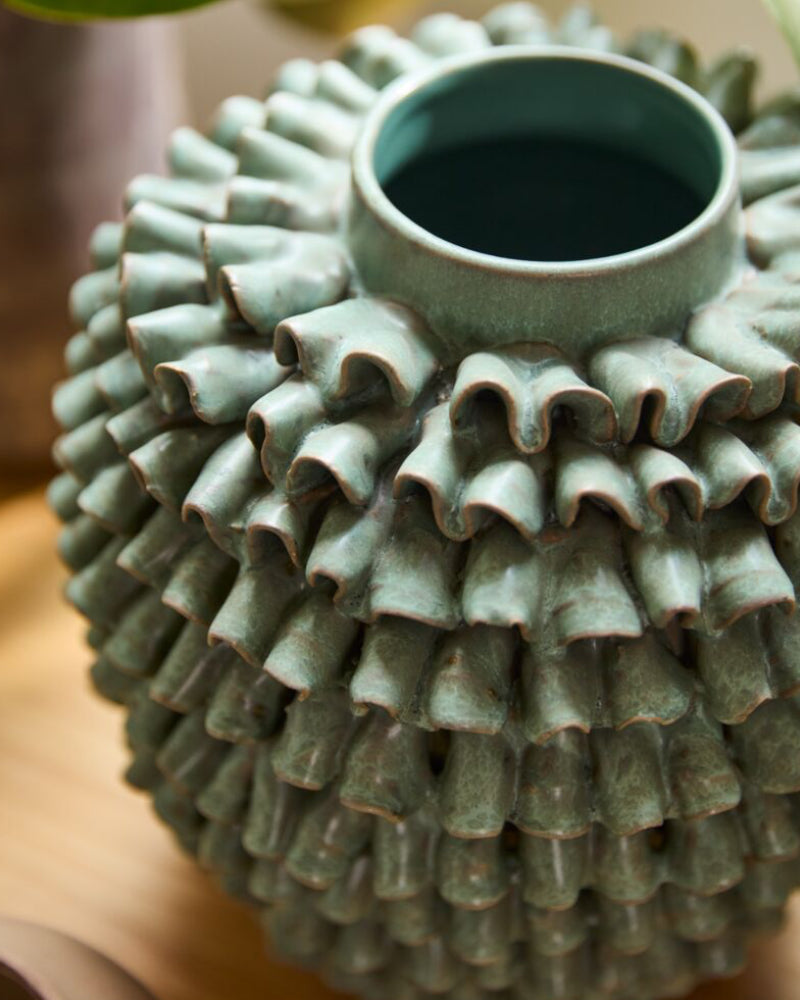 Decorative ceramic vase with textured design on a blurred background