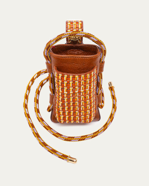 Brown leather and woven straw bag with a strap on a light beige background