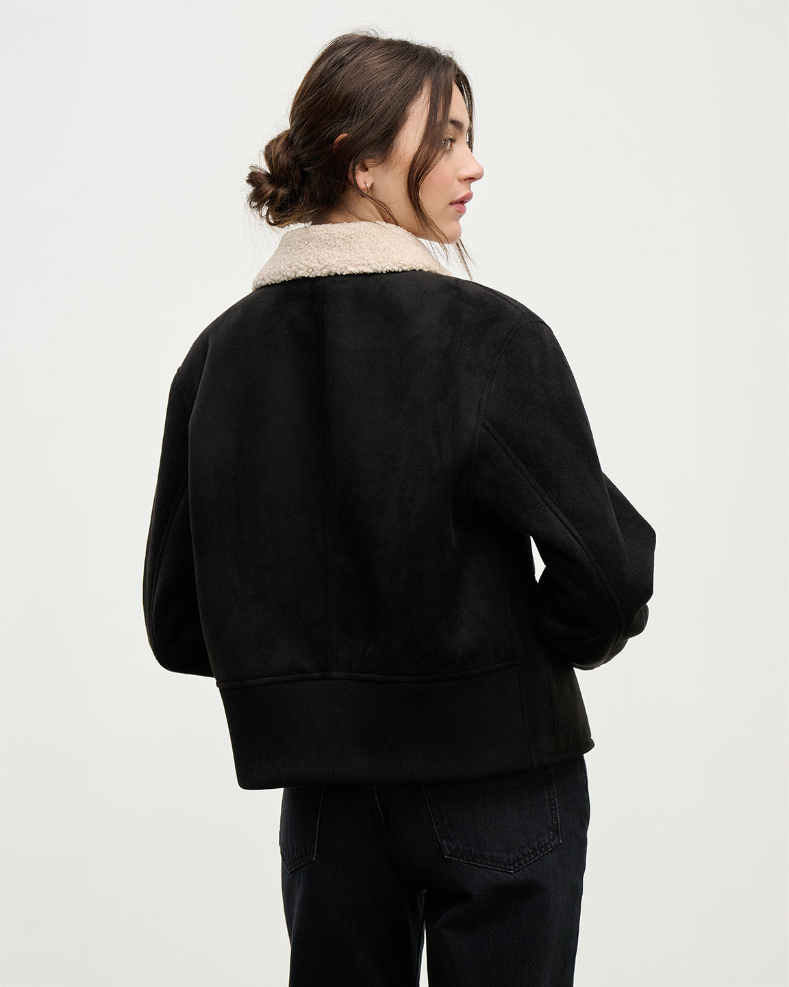Person wearing a black jacket with a beige collar on a white background