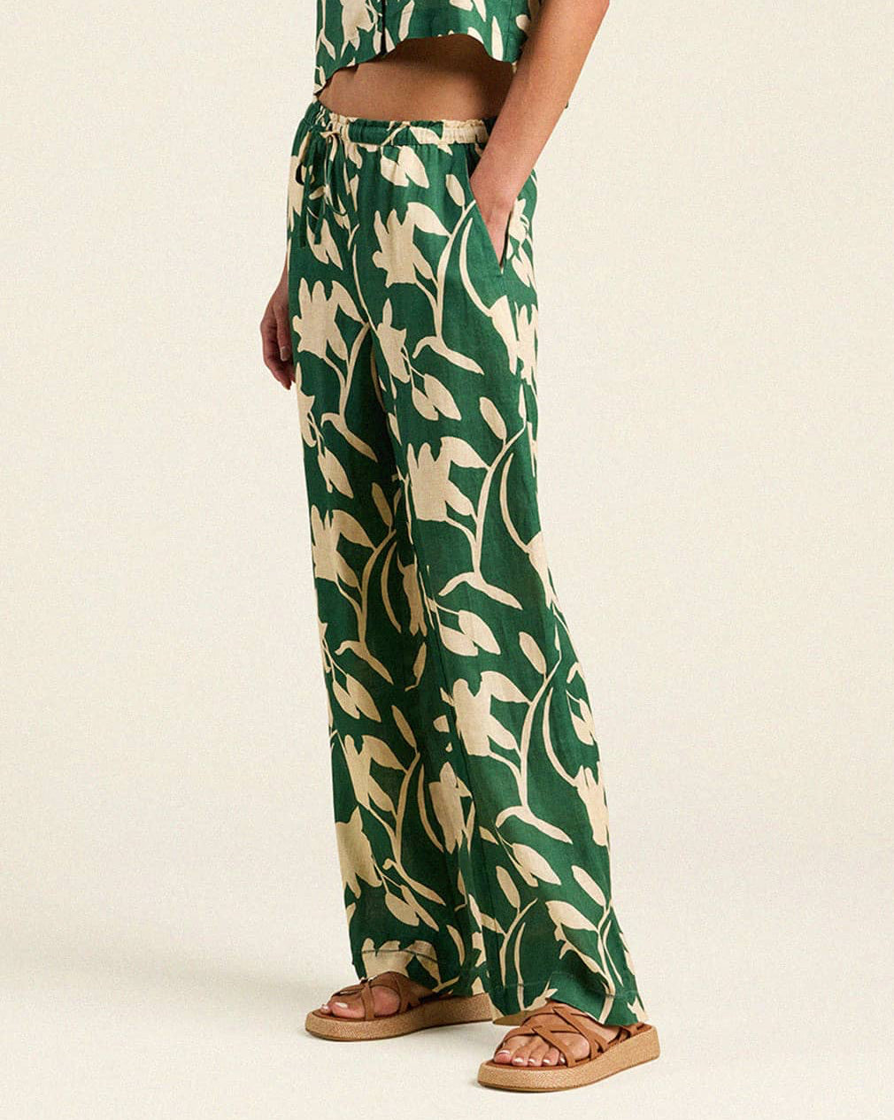 Person wearing a green and beige patterned outfit on a plain background