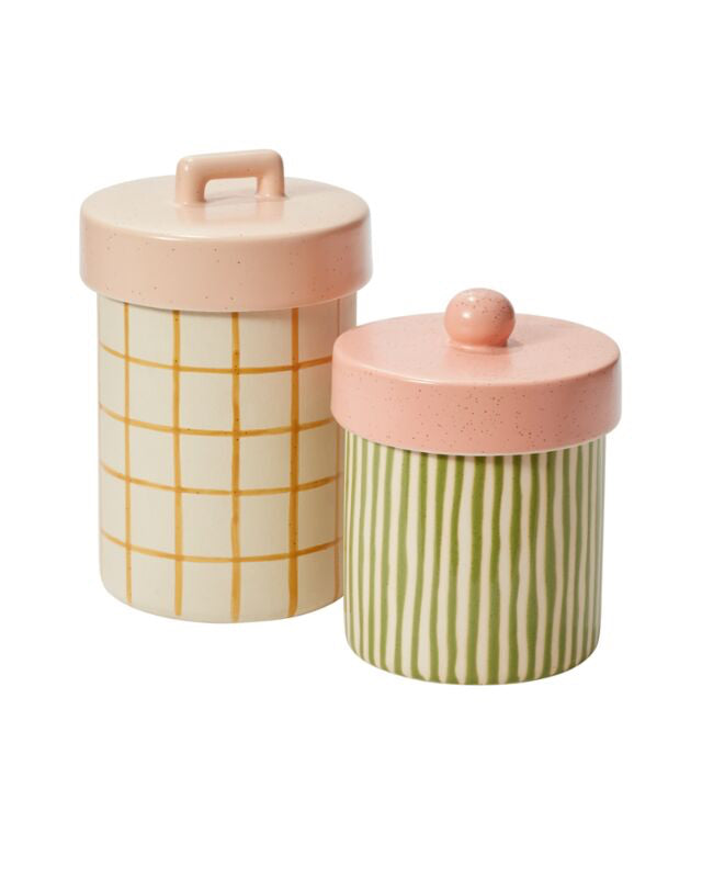Two ceramic storage jars with pink lids on a white background