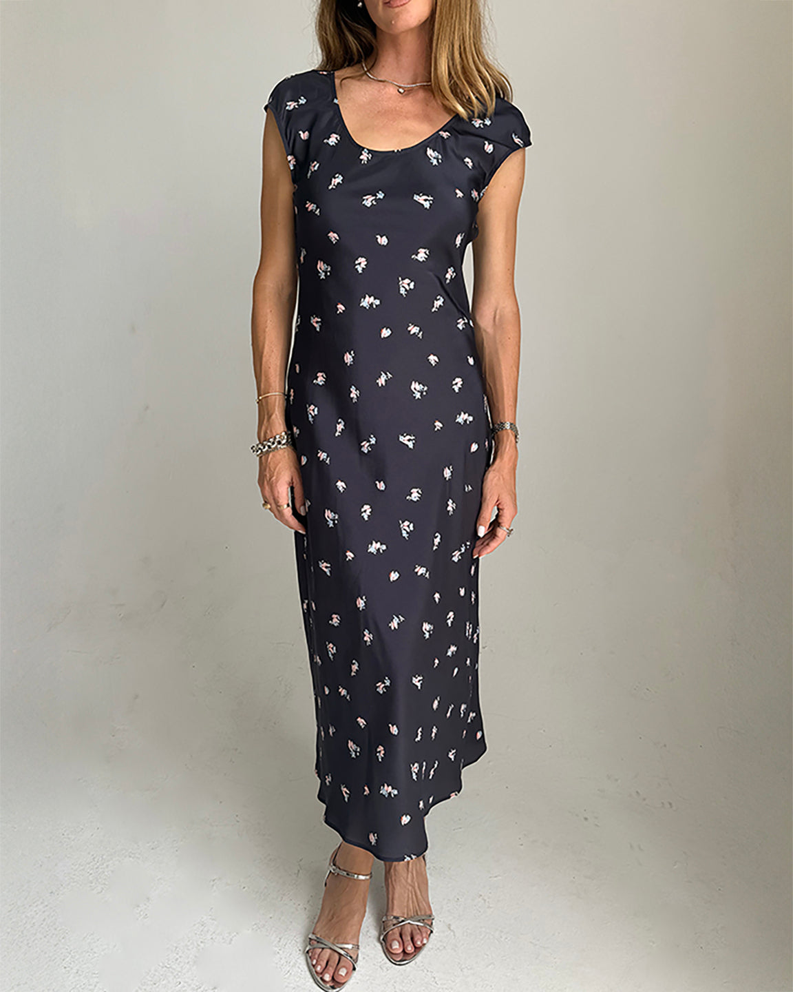 Woman wearing a  black dress with white floral pattern on a plain background