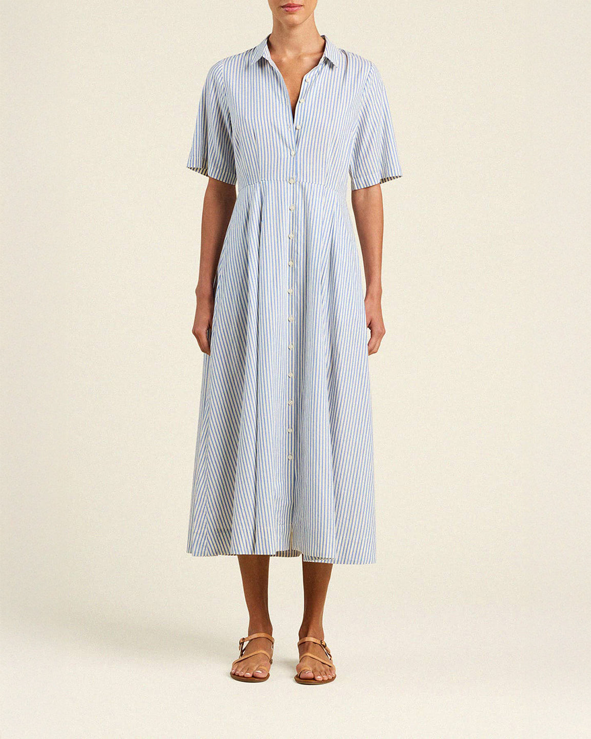 Woman wearing a blue and white striped dress on a beige background