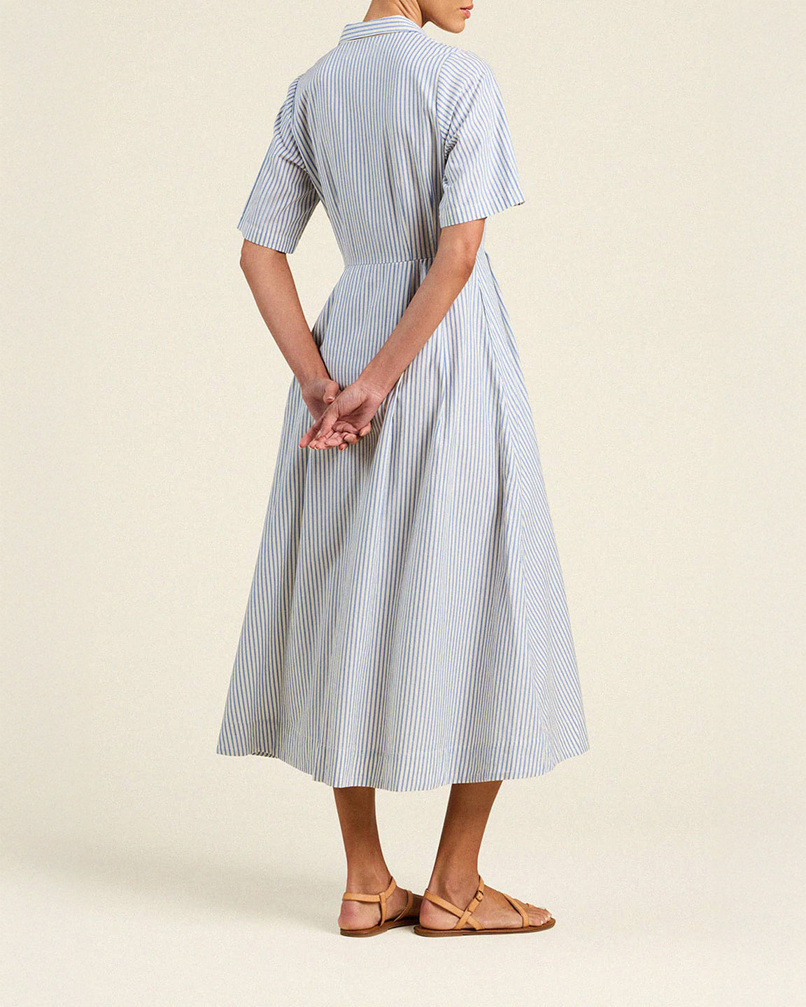 Woman wearing a blue and white striped dress on a beige background