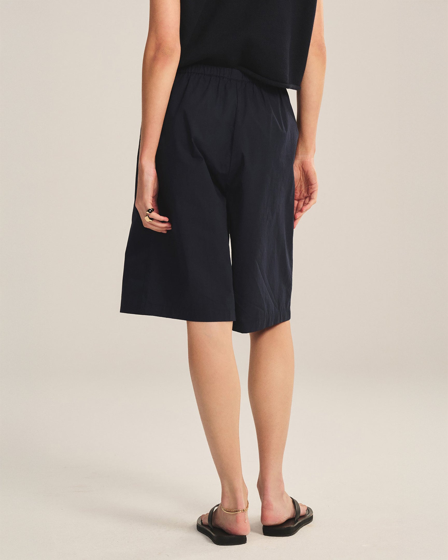 Person wearing black shorts on a beige background