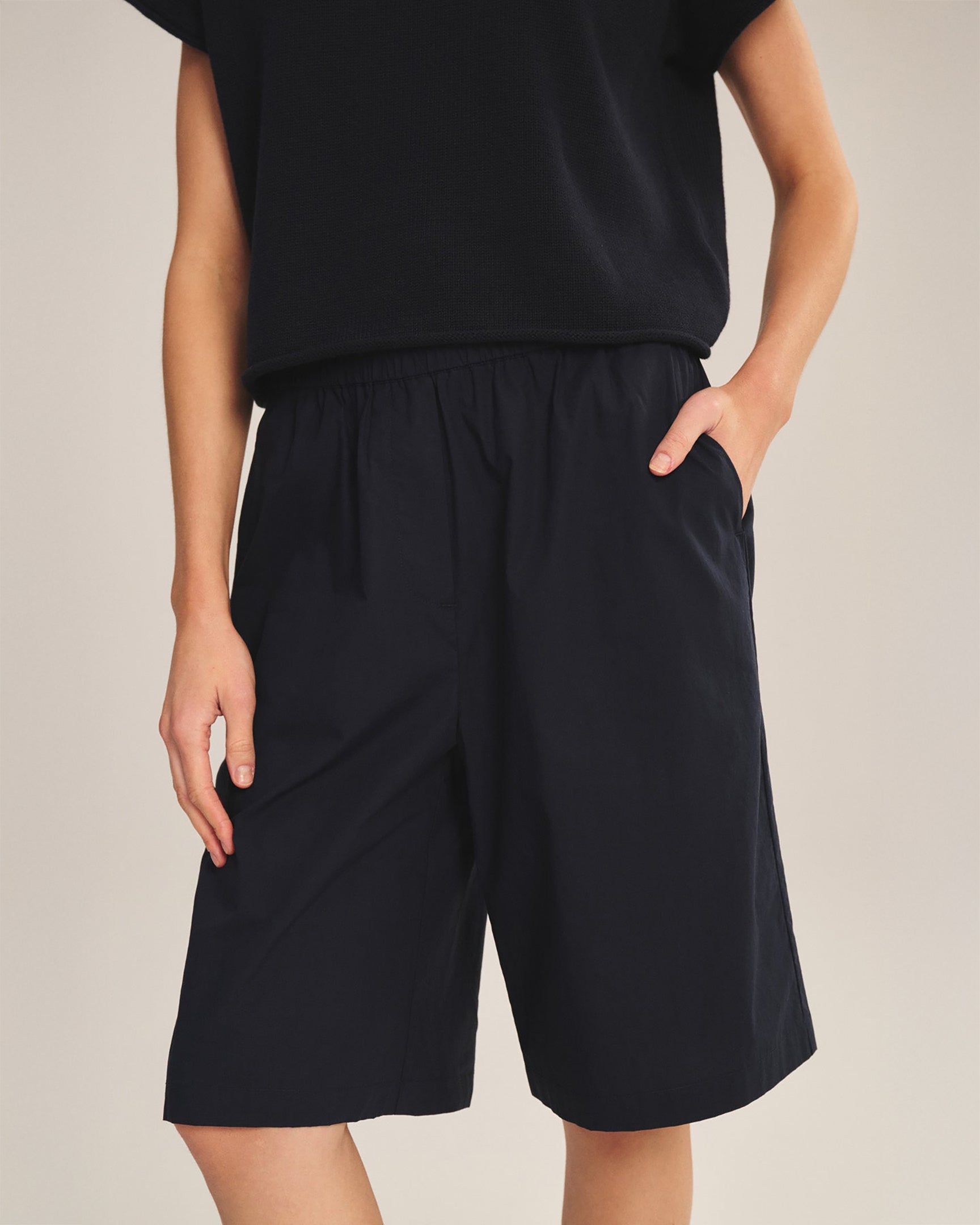 Person wearing black shorts and a black top on a plain background