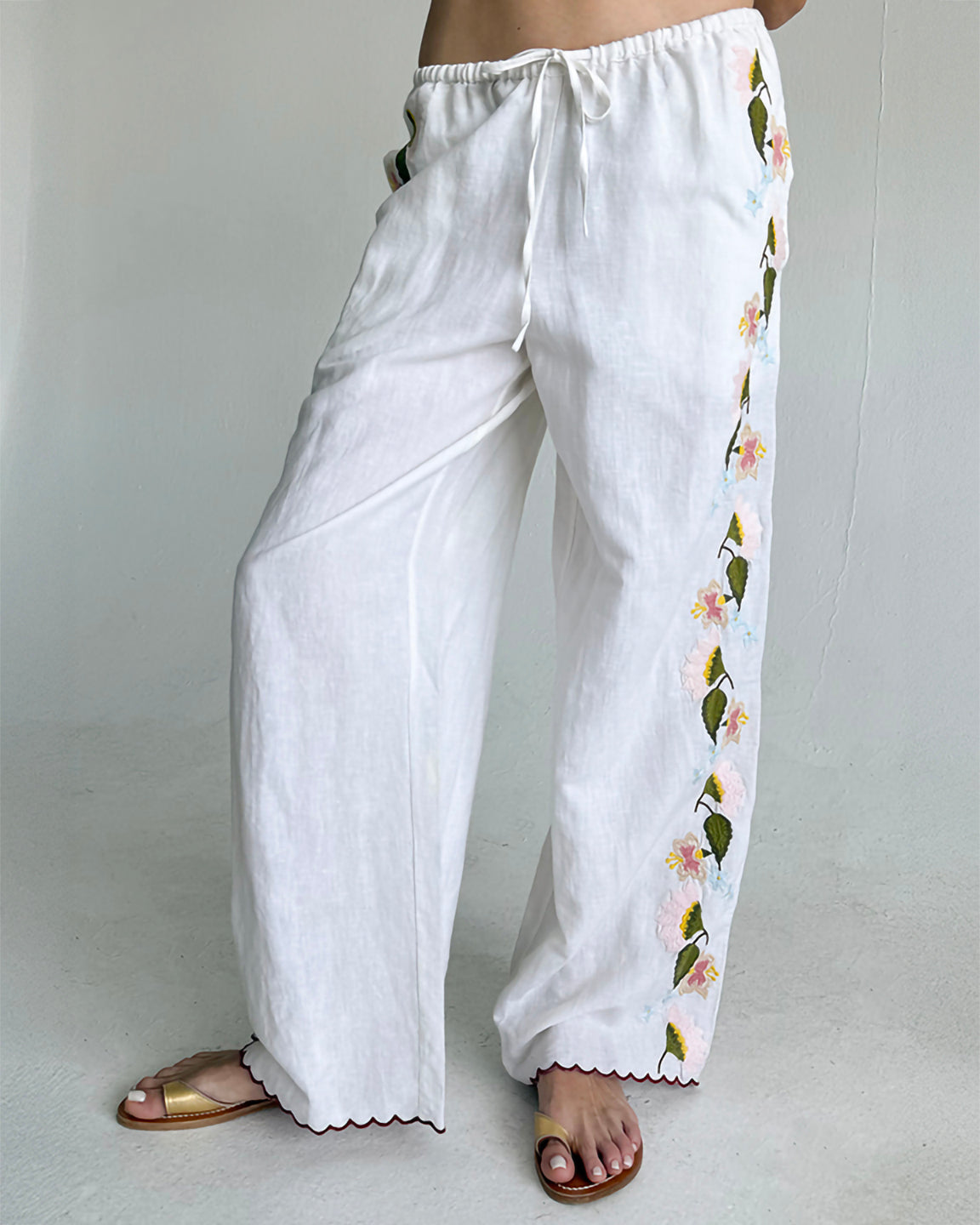 White pants with floral embroidery on a plain background
