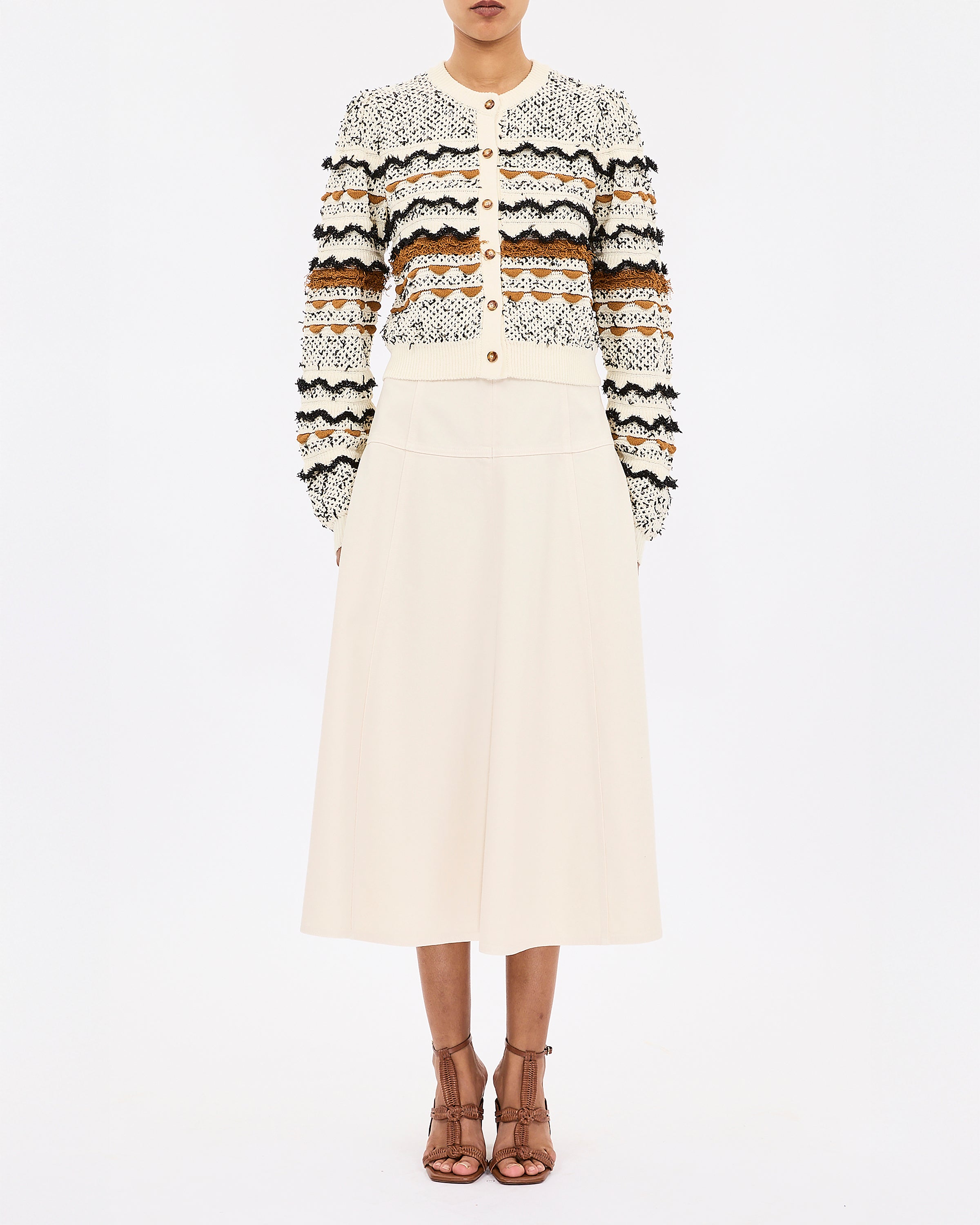 Person wearing a patterned sweater and white skirt on a white background