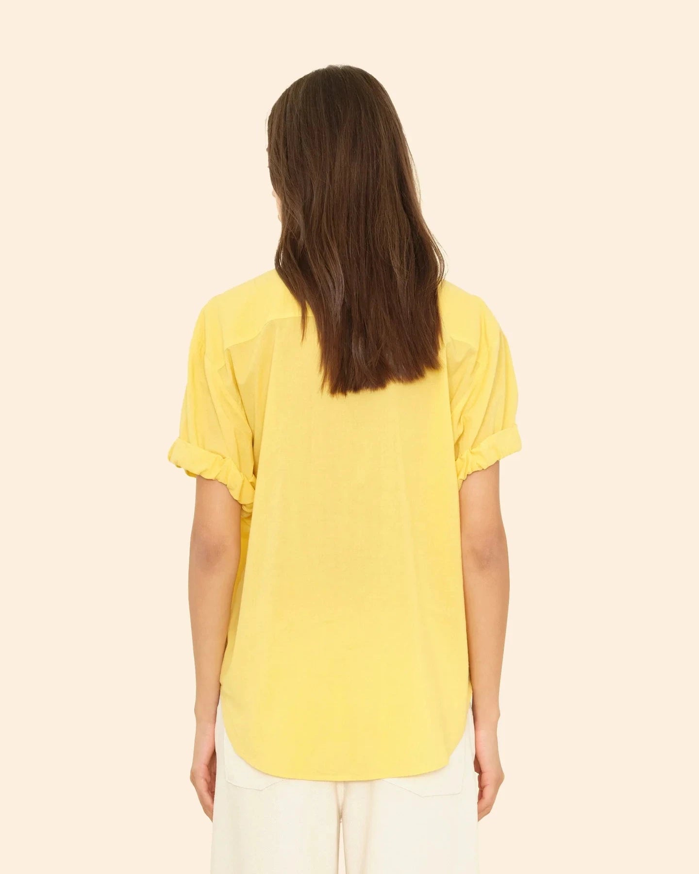 Person wearing a yellow t-shirt on a beige background