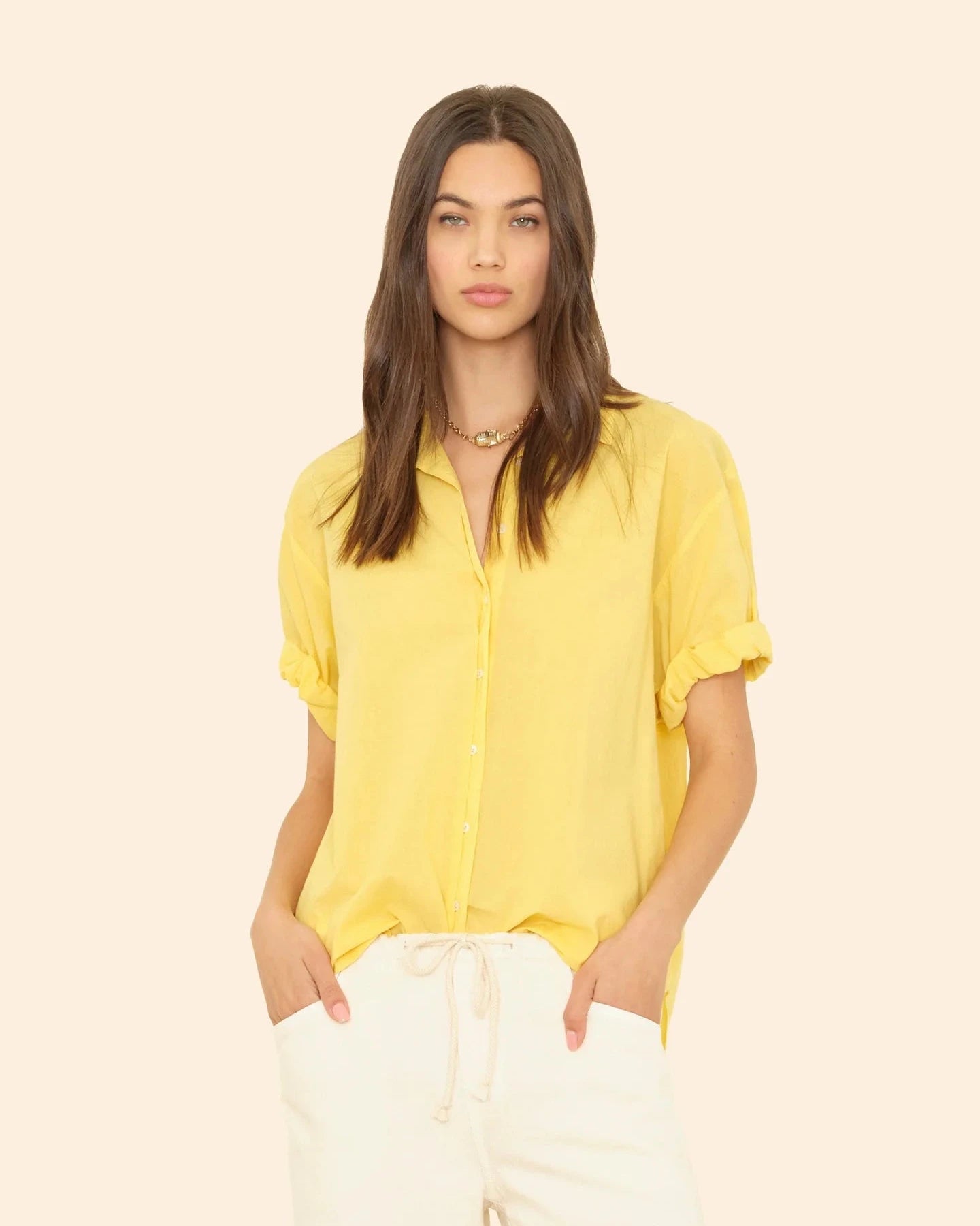 Woman wearing a yellow blouse against a beige background