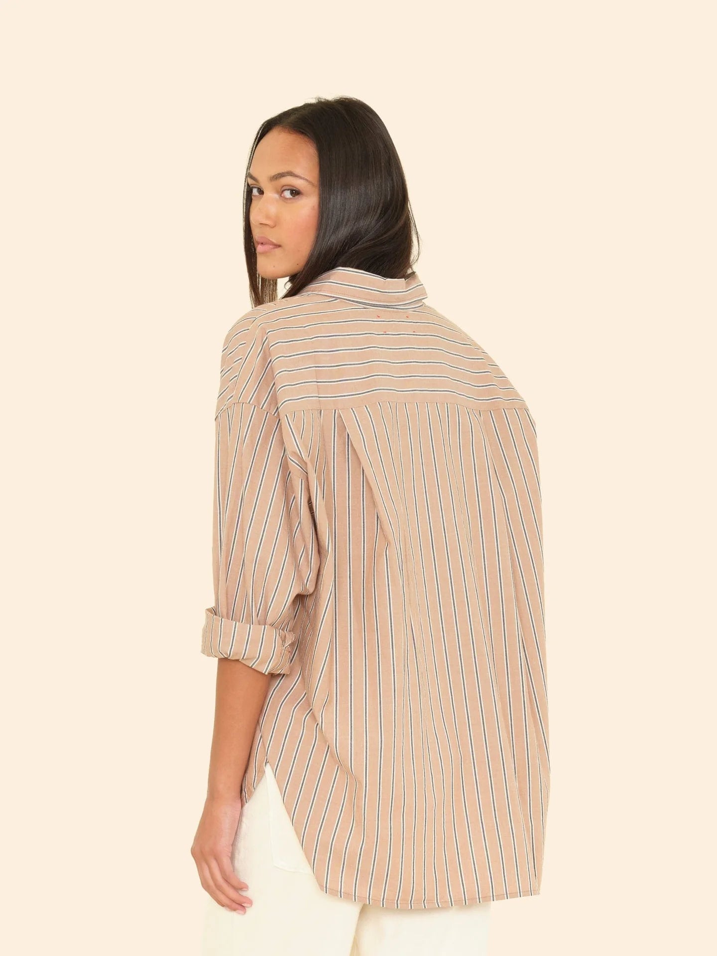 Woman wearing a beige striped shirt on a plain background
