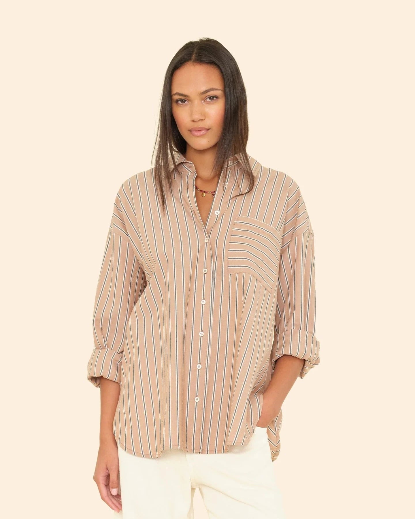 Woman wearing a striped shirt against a beige background