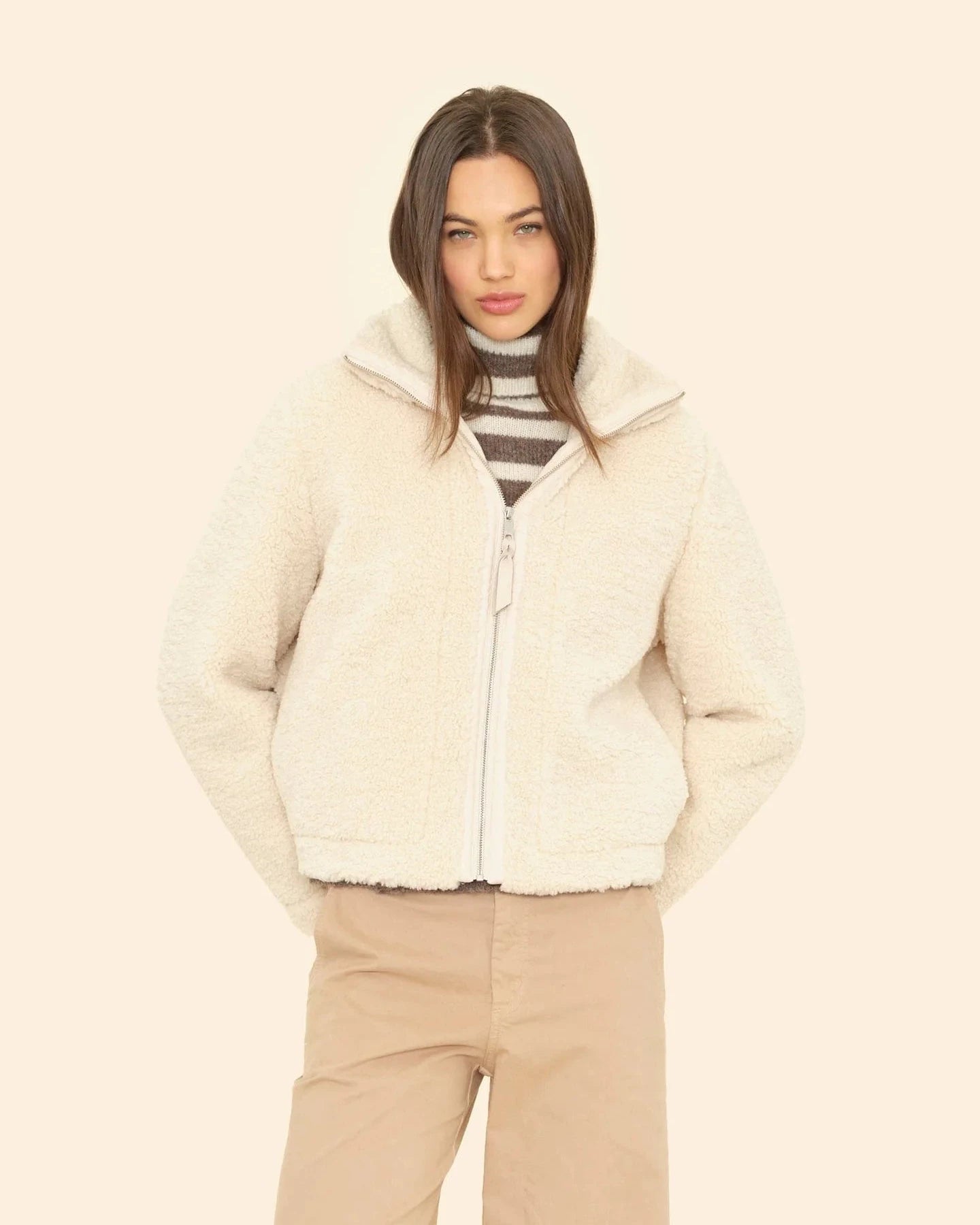 Woman wearing a cream puffer jacket on a beige background