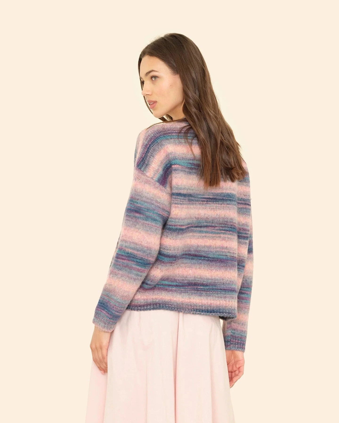 Woman wearing a striped sweater and light pink pants on a beige background