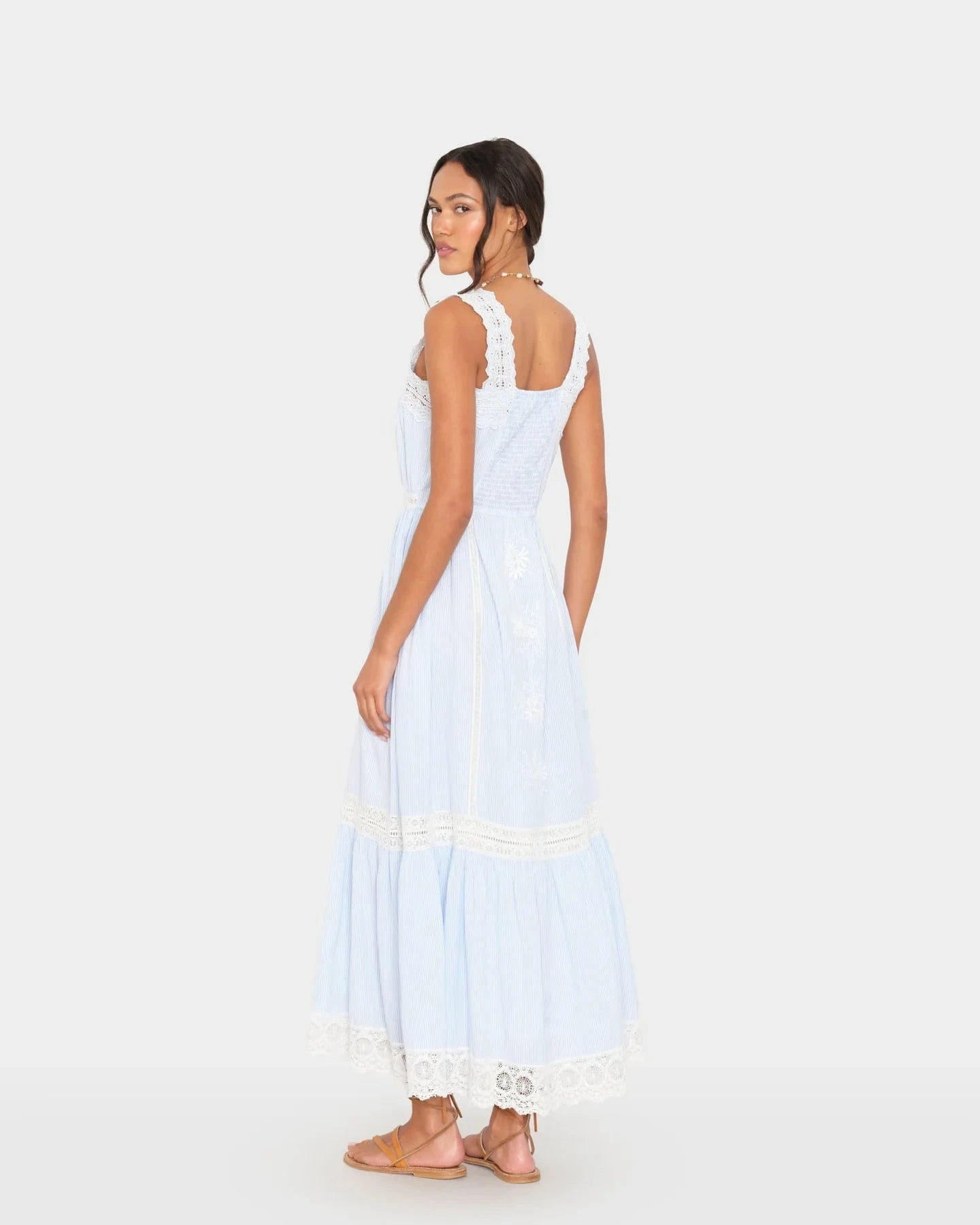 Woman wearing a white and light blue dress with lace details on a white background
